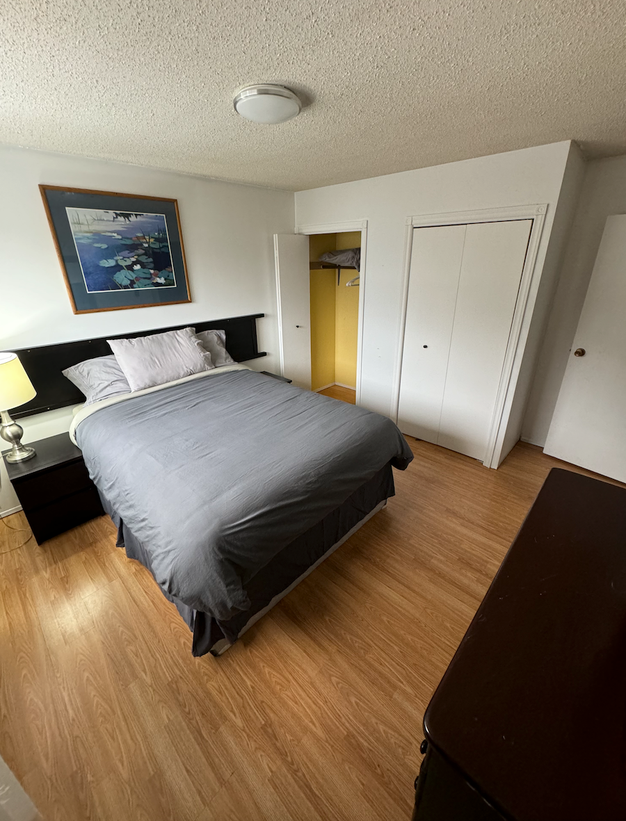 A bedroom with a bed , nightstand , dresser and a picture on the wall.