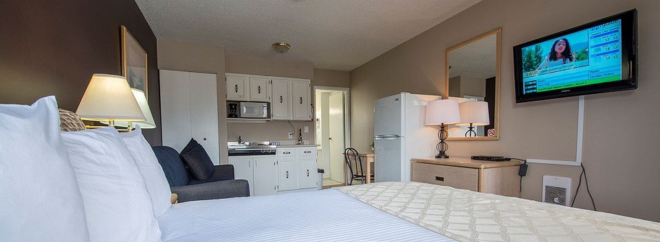 A hotel room with a bed , couch , television and kitchen.