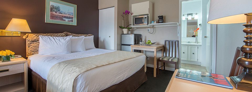 A hotel room with a bed , desk , chair and lamp.