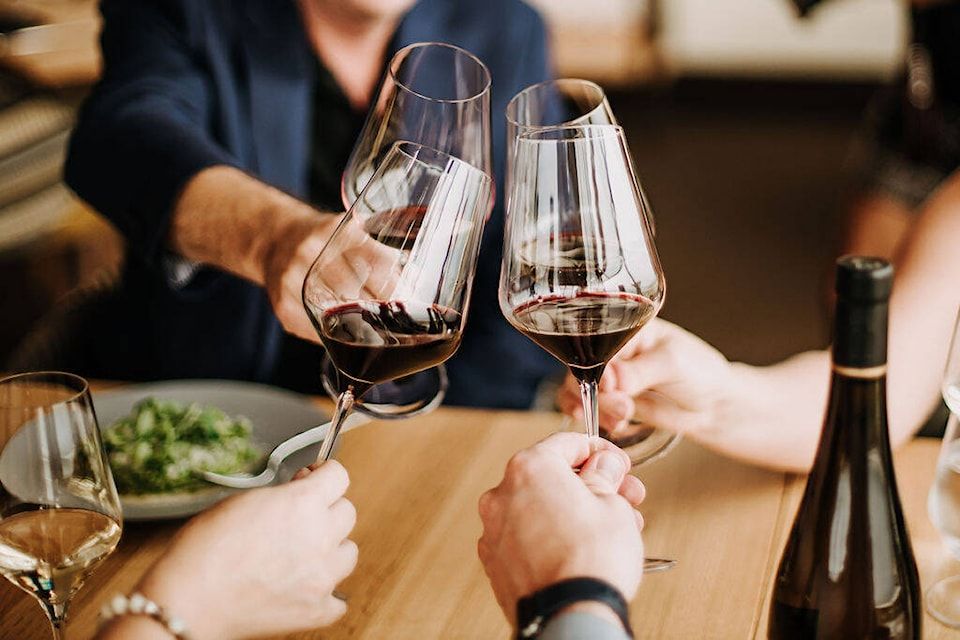 A group of people are toasting with wine glasses at a table.