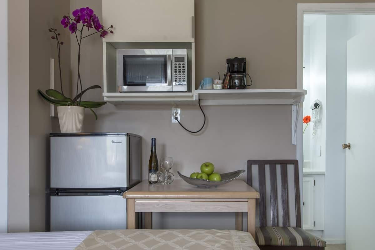 A small kitchen with a refrigerator , microwave , table and chairs.