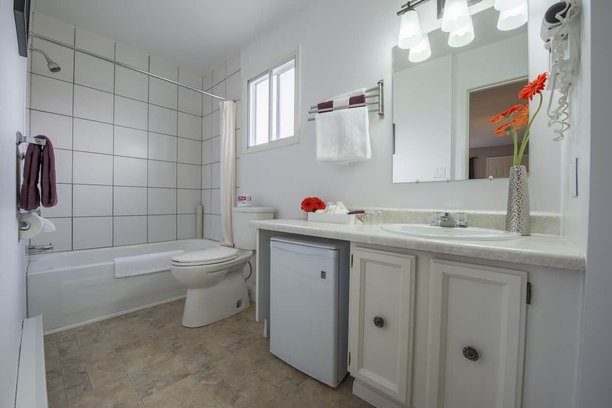 A bathroom with a toilet , sink , tub and mirror.