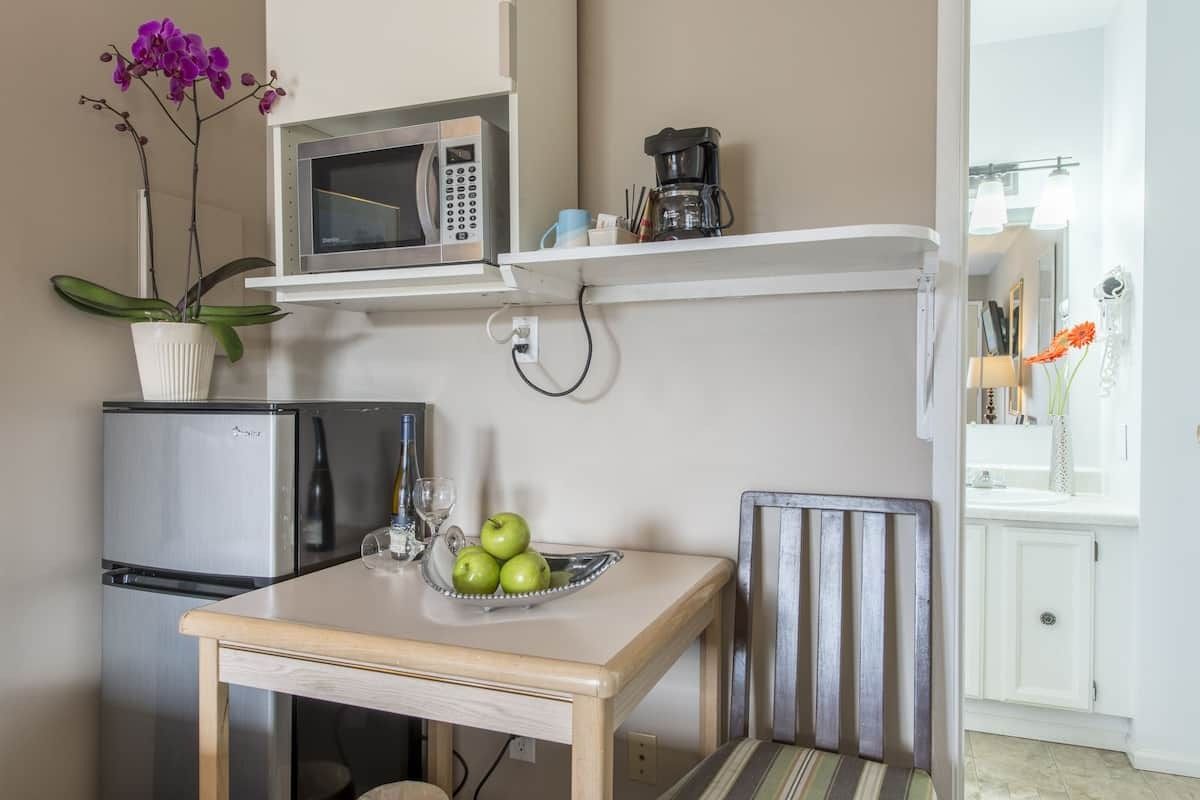 A small table with a bowl of apples on it in a kitchen.