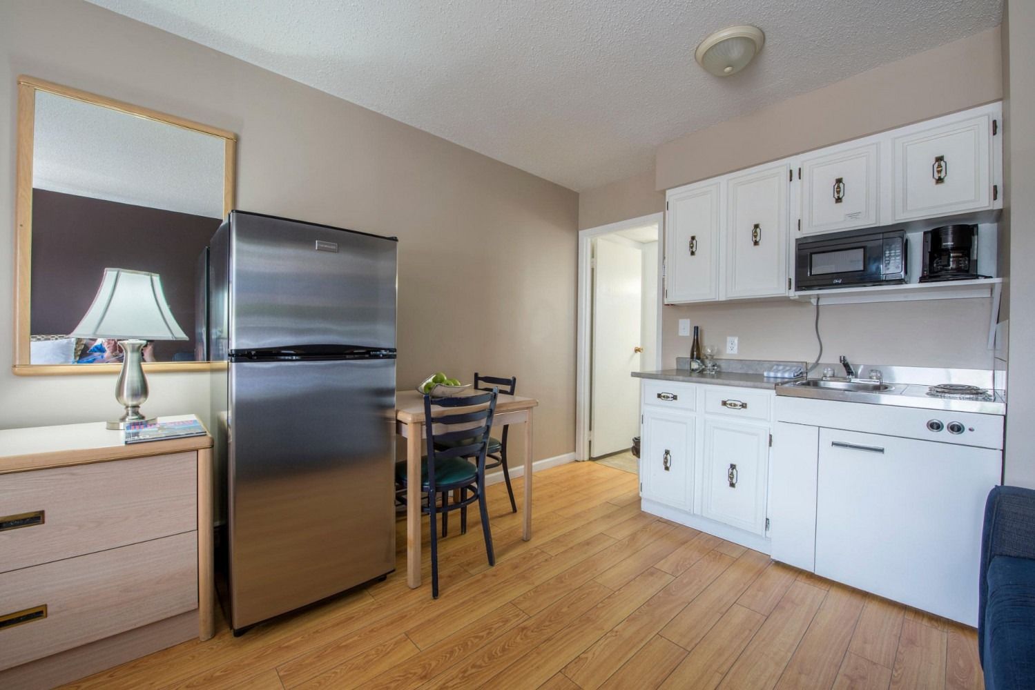 A kitchen with a refrigerator , microwave , sink , table and chairs.