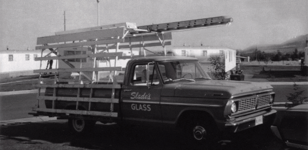 A person installing a solar panel on a gray corrugated metal roof.