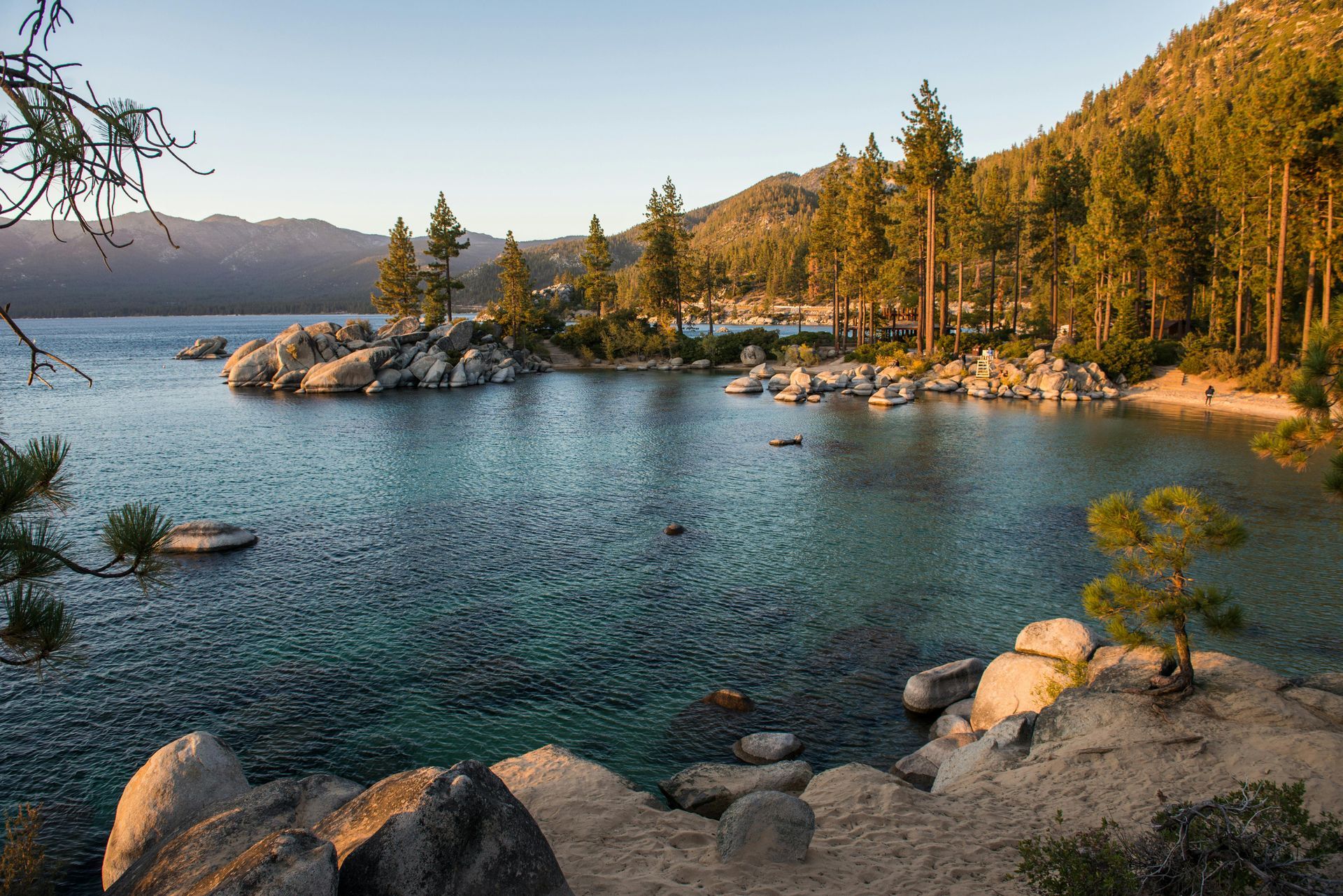 A group of people are walking across a bridge over a river in a park.