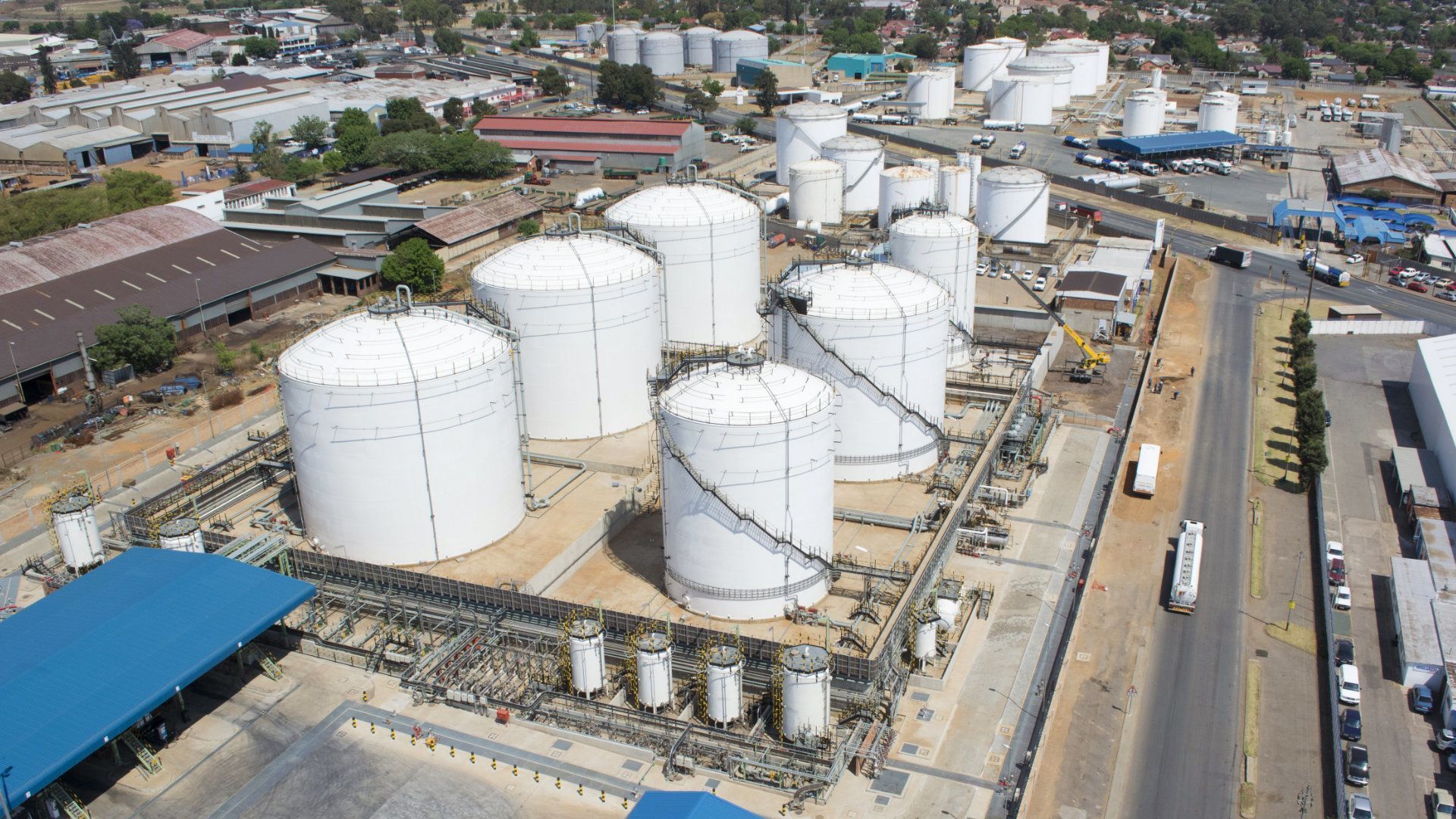 Aerial view of a large oil storage facility with several white cylindrical tanks and buildings.