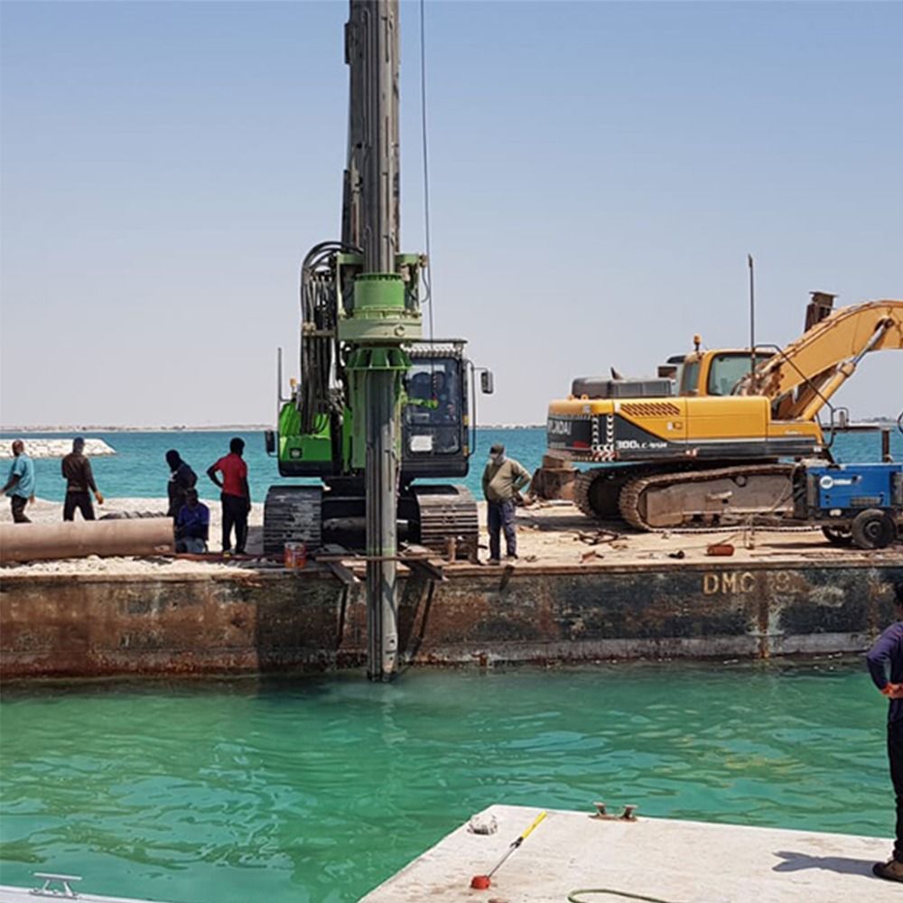 Construction site on water. A drilling machine and excavator on a barge near the sea. People observe.