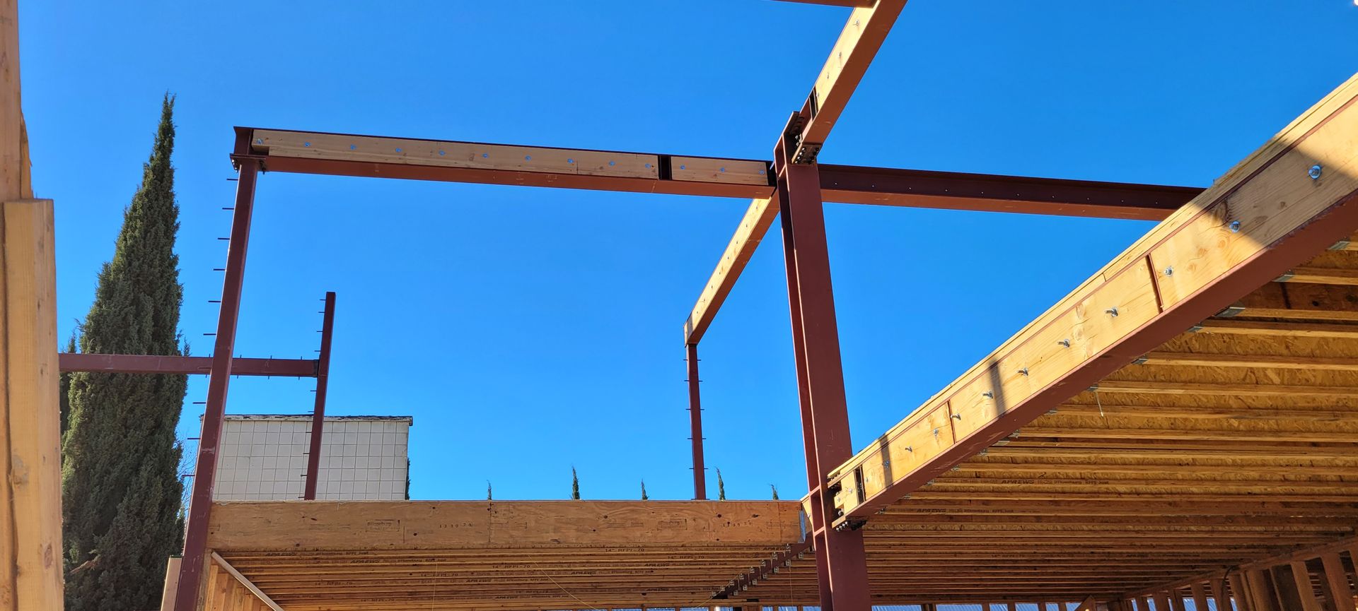 Construction site with exposed steel beams and wood framing against a blue sky.
