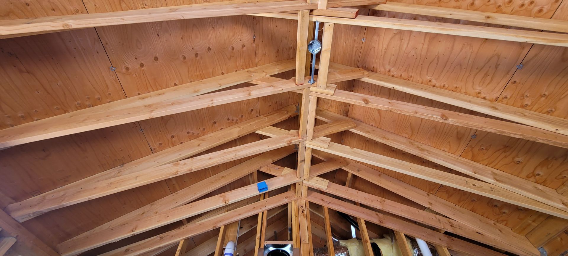Wooden rafters and sheathing of a ceiling. Blue electrical box visible.