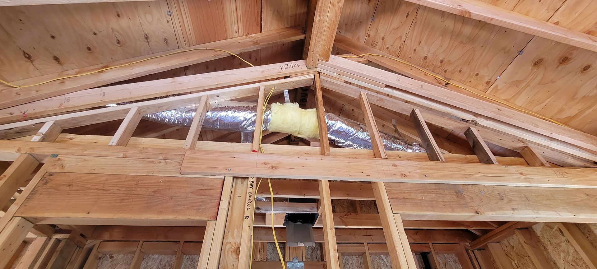 Wooden framing of a ceiling and upper wall in a construction site.