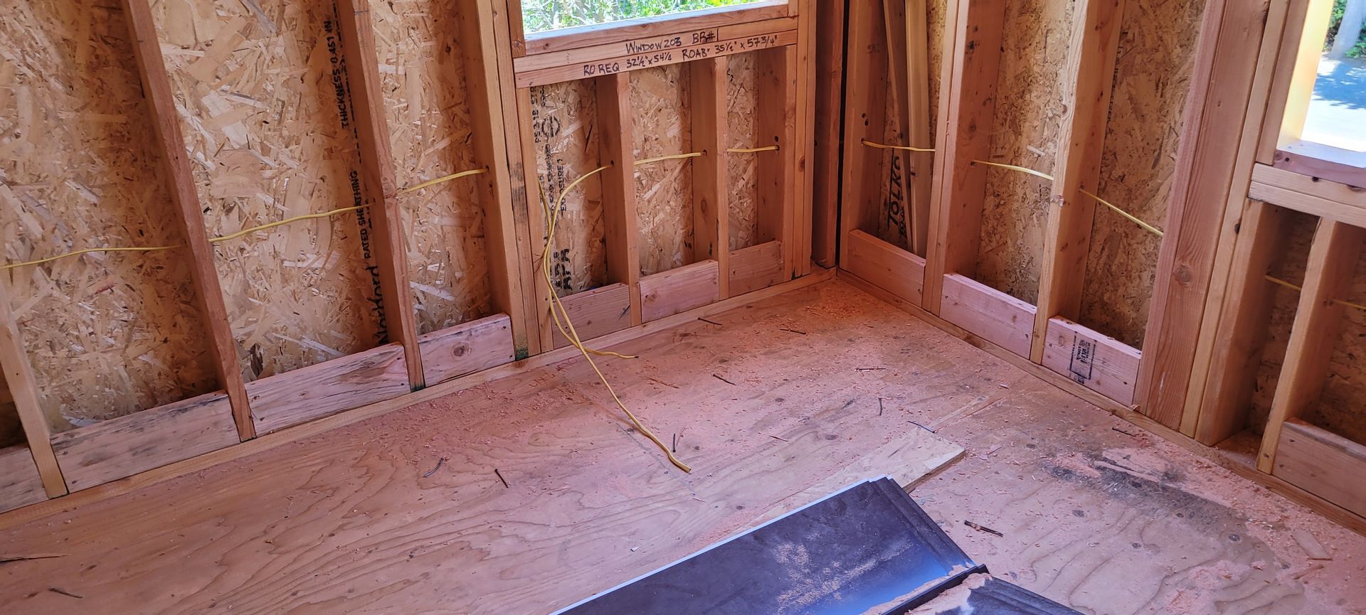 Interior framing of a building under construction. Walls and floor made of wood and a window.
