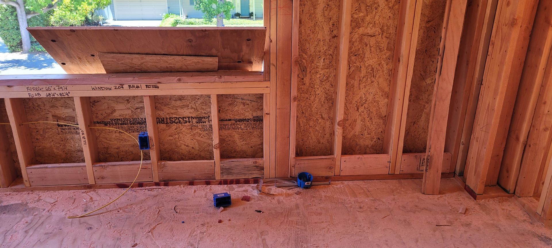 Interior view of a building under construction, showing wooden framing, an opening, and two electrical boxes.