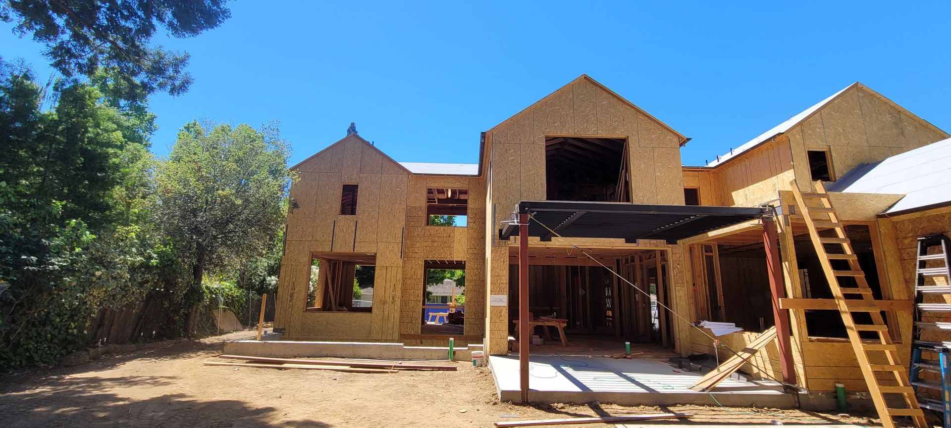 House under construction; exposed wooden frame; clear blue sky.