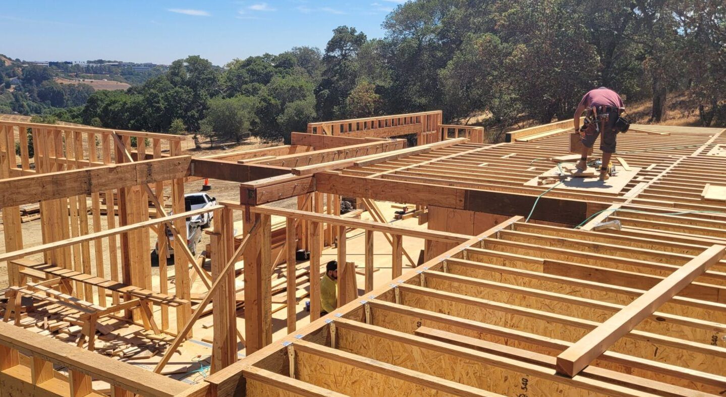Construction of a house frame with workers on site, exterior view. 