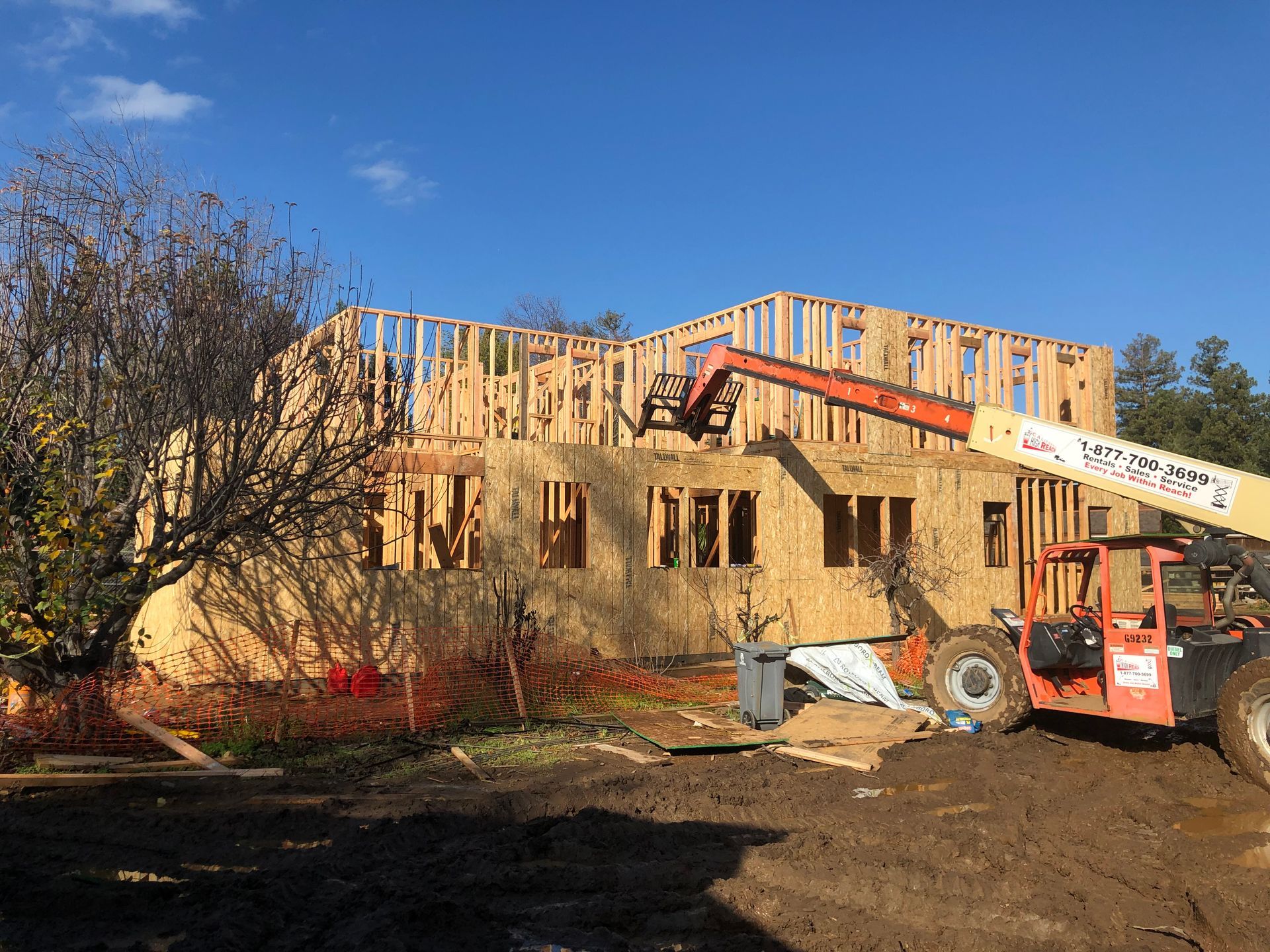 House under construction; wooden frame and OSB siding; blue sky in the background.