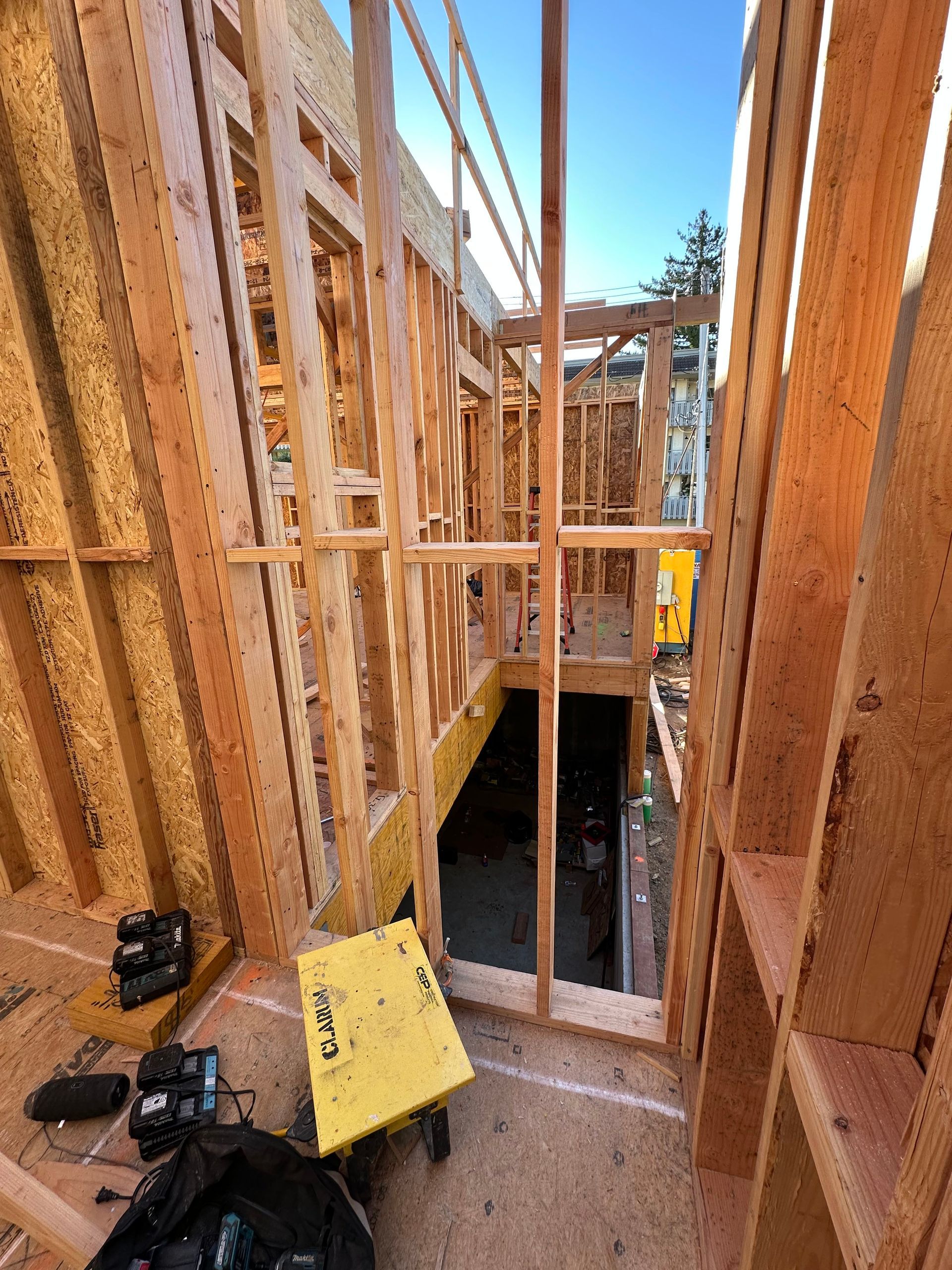 Interior view of wooden house framing with staircase opening. 