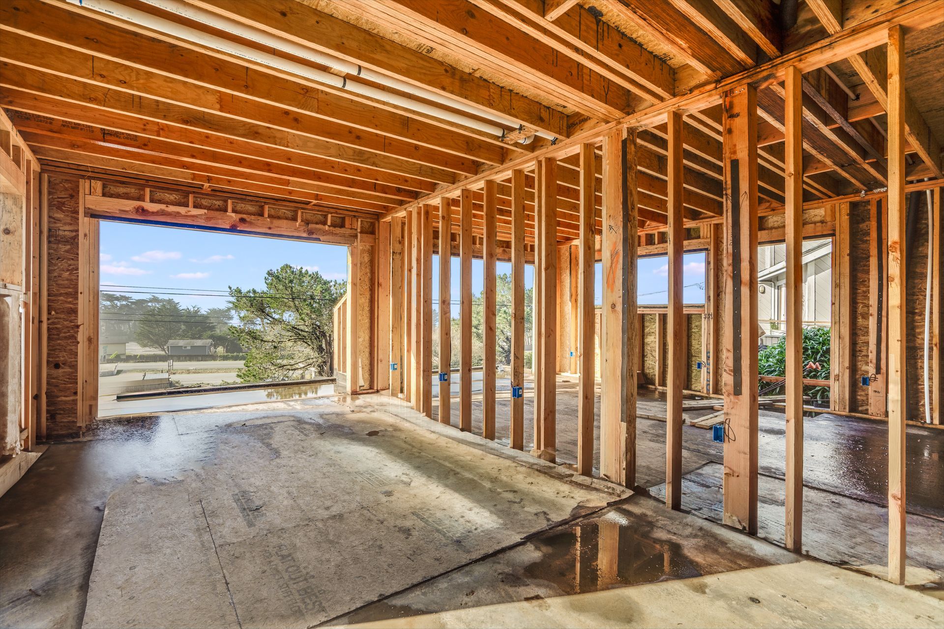 Wooden frame of a building interior under construction, with open doorway and windows.