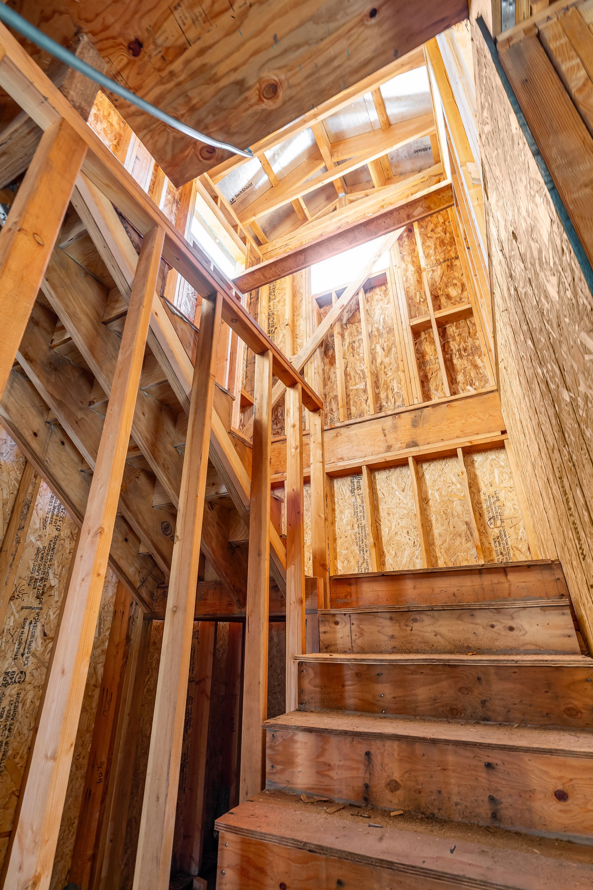 Wooden staircase in unfinished building with access to natural light.