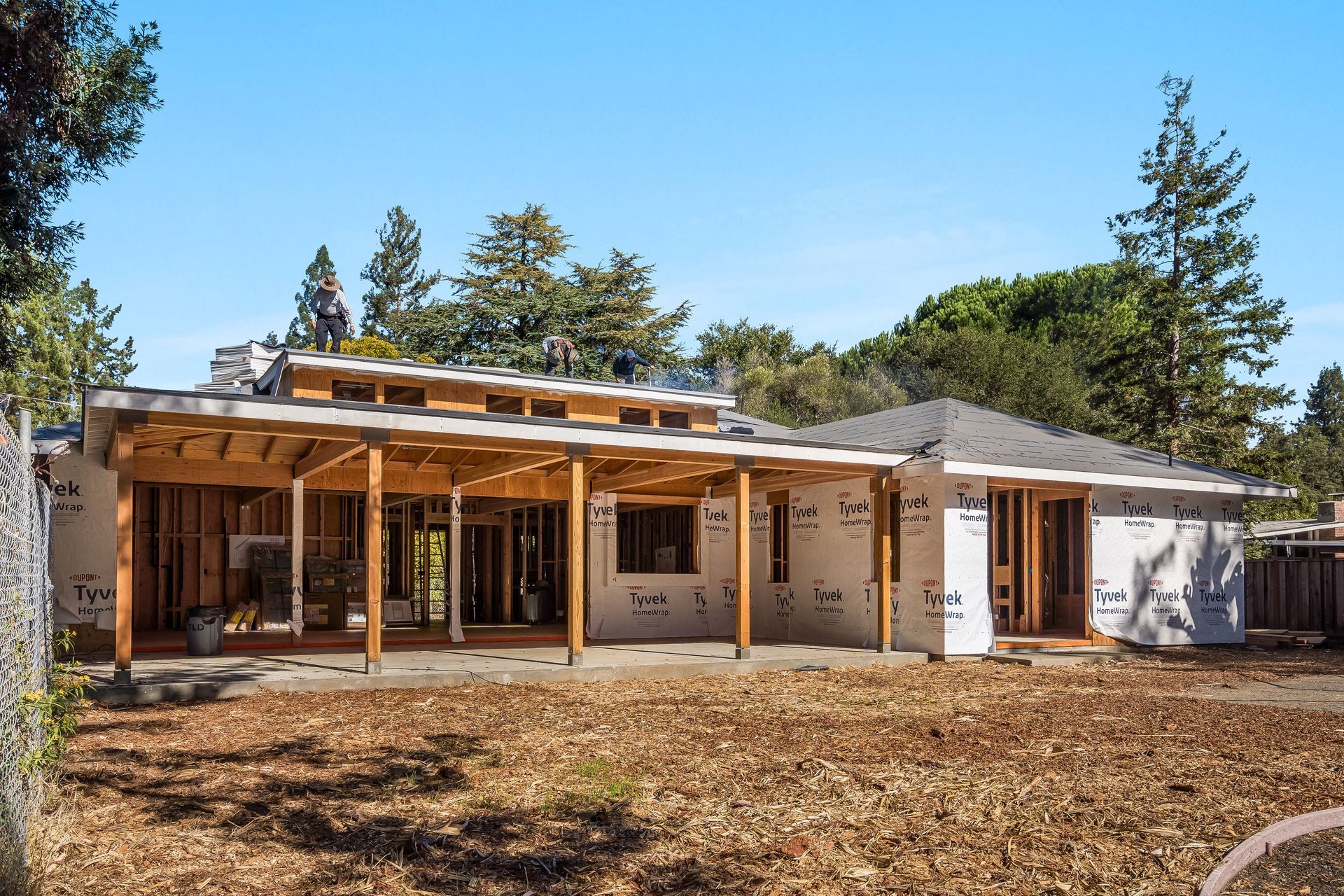 House under construction with exposed wooden frame and sheathing, sunny day.