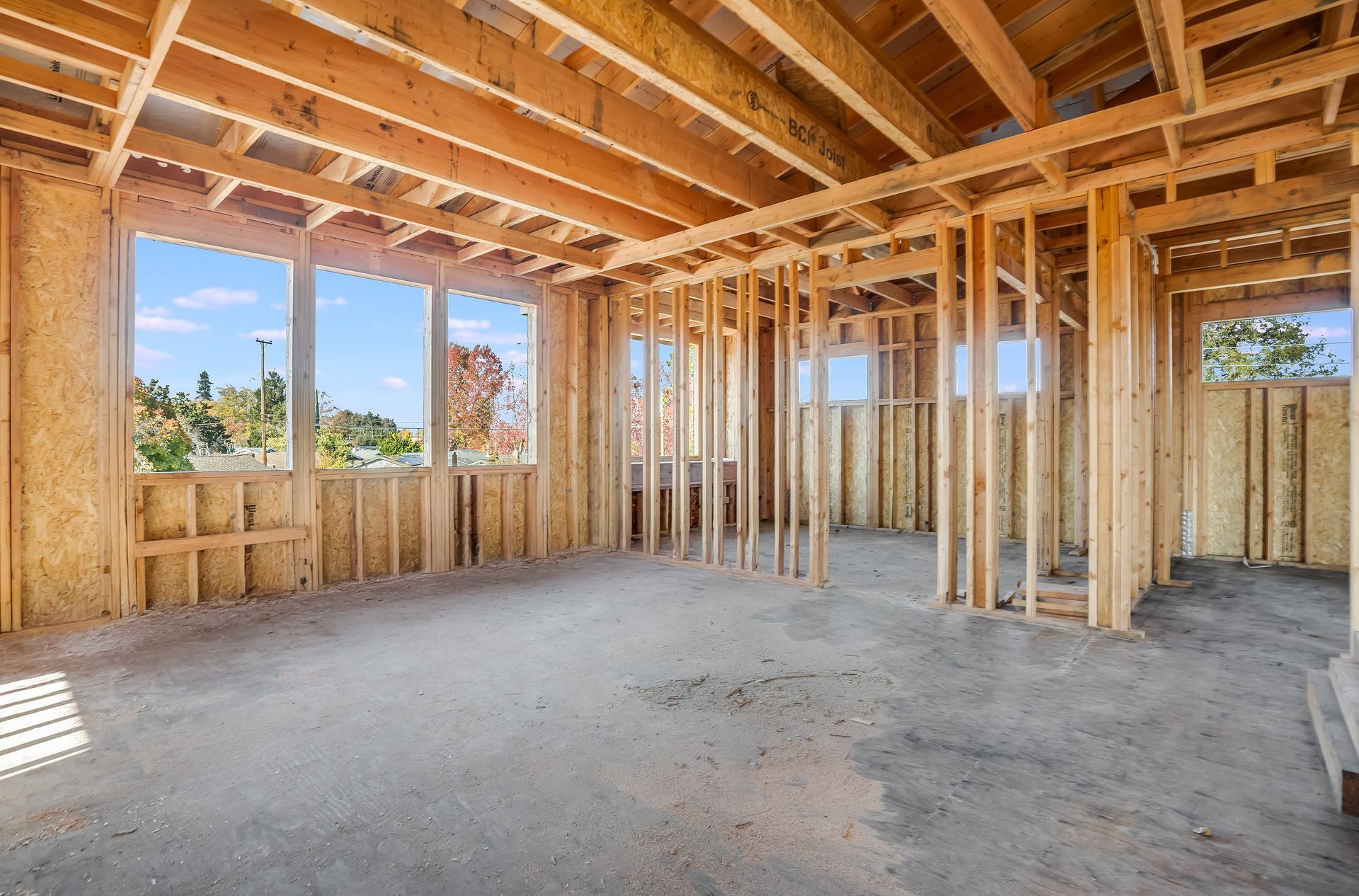 Interior of a house under construction; wooden framework, windows, and bare concrete floor.