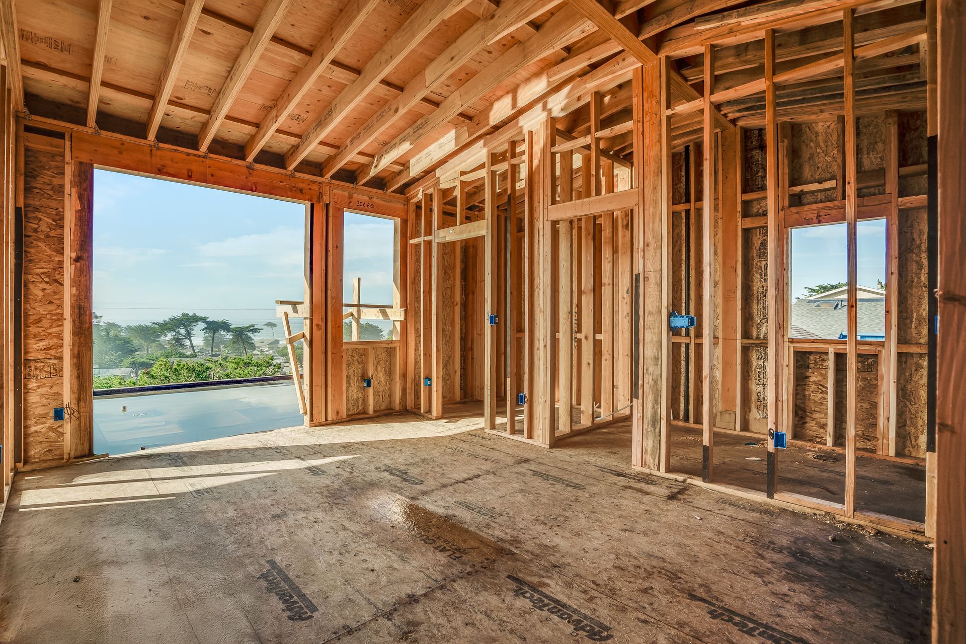 Interior of a house under construction. Wooden framing, large window, and unfinished floor.