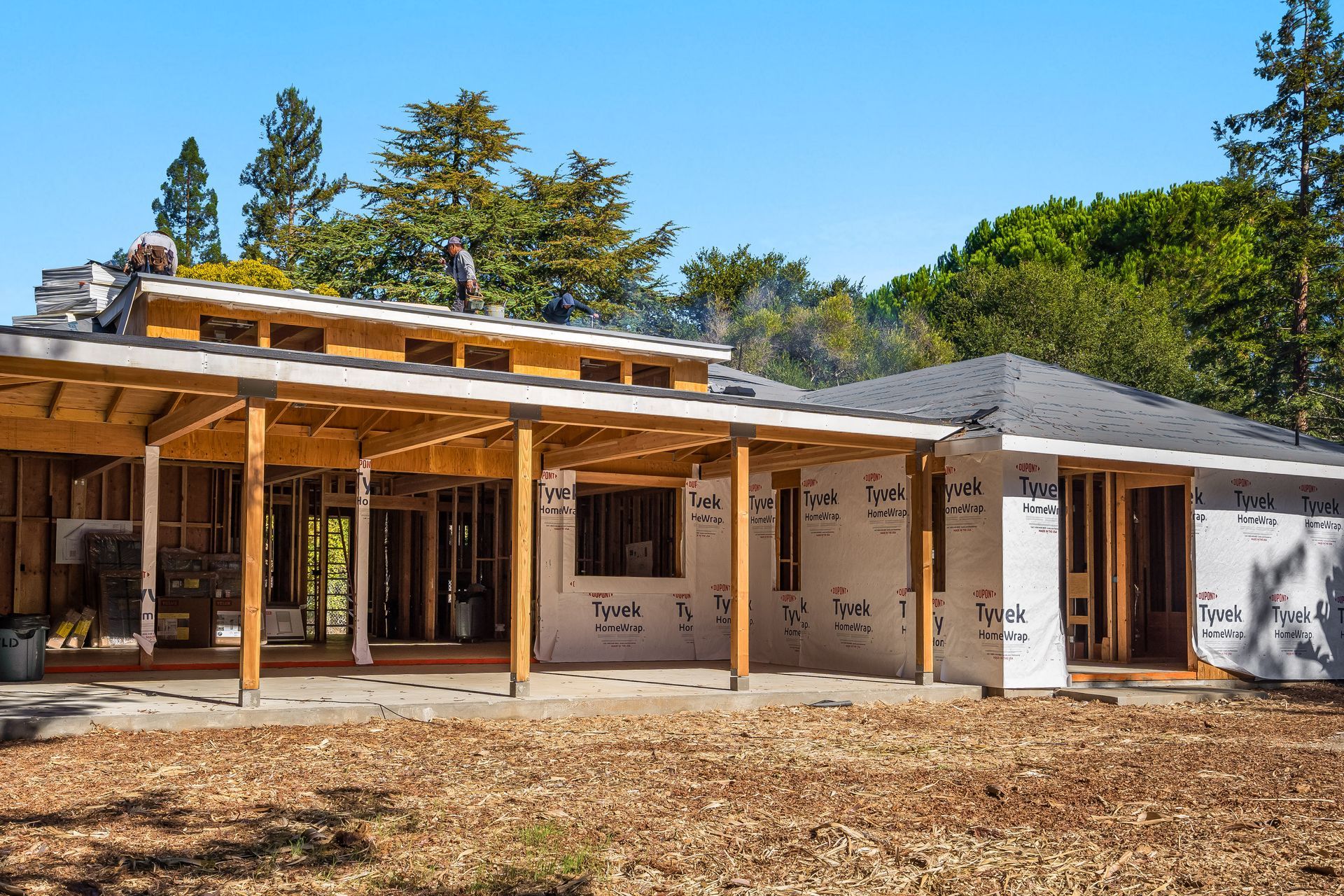 Two-story house under construction, wooden frame visible. Includes attached garage and construction materials.