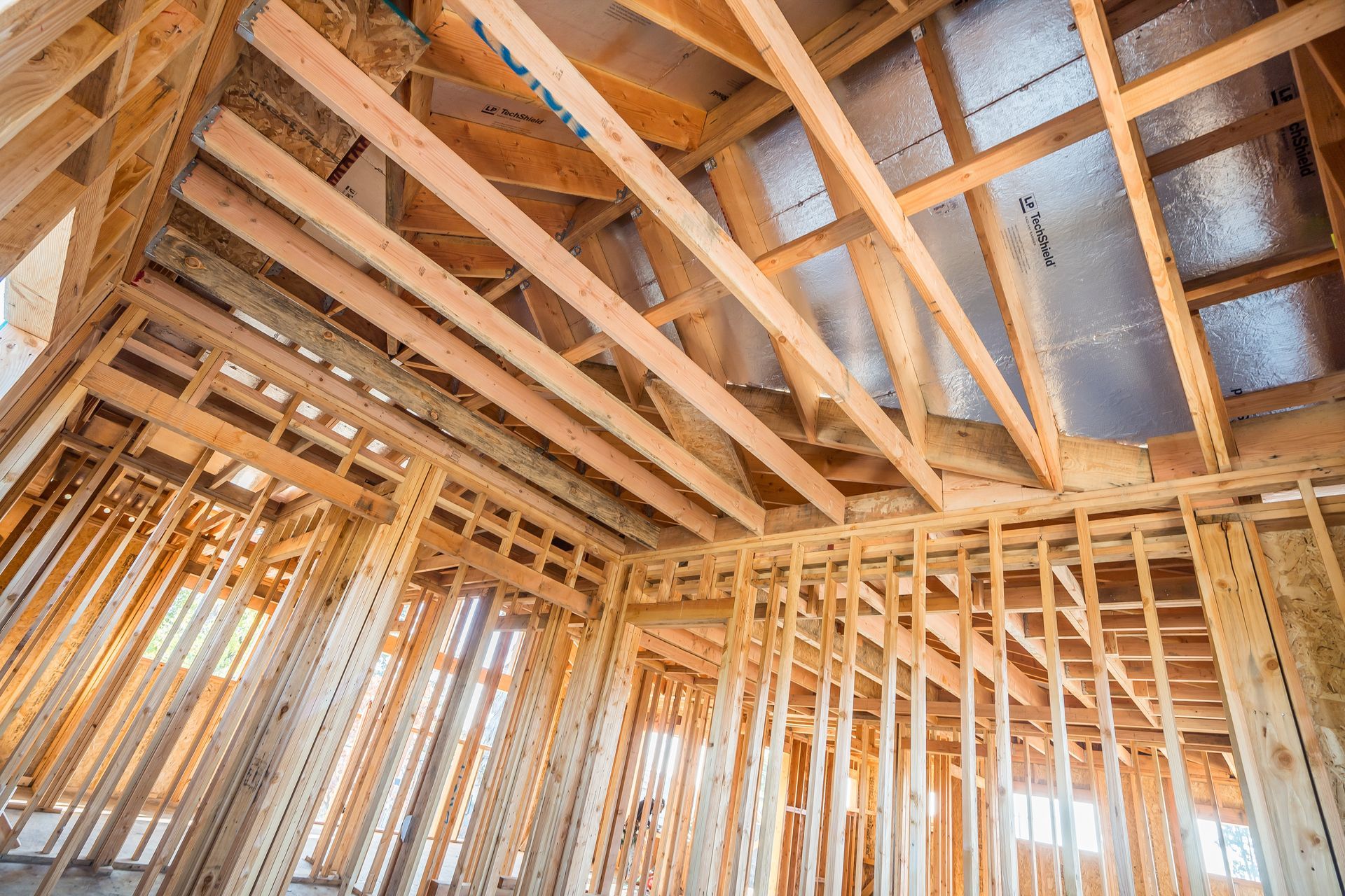 Interior view of a building under construction, wooden framework, open beams, and insulation.
