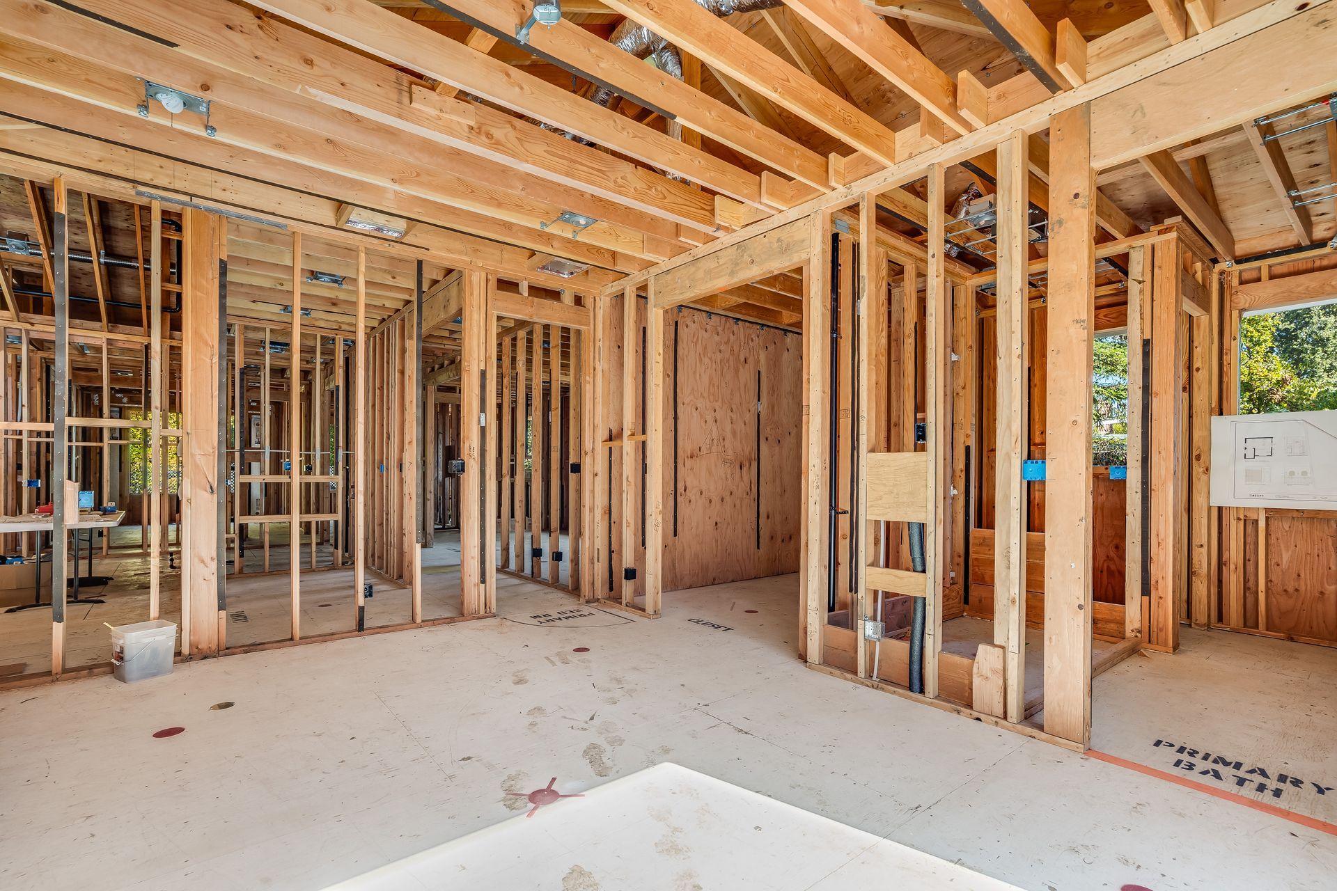 Interior of a building under construction, wooden frames, exposed beams, and concrete floor.