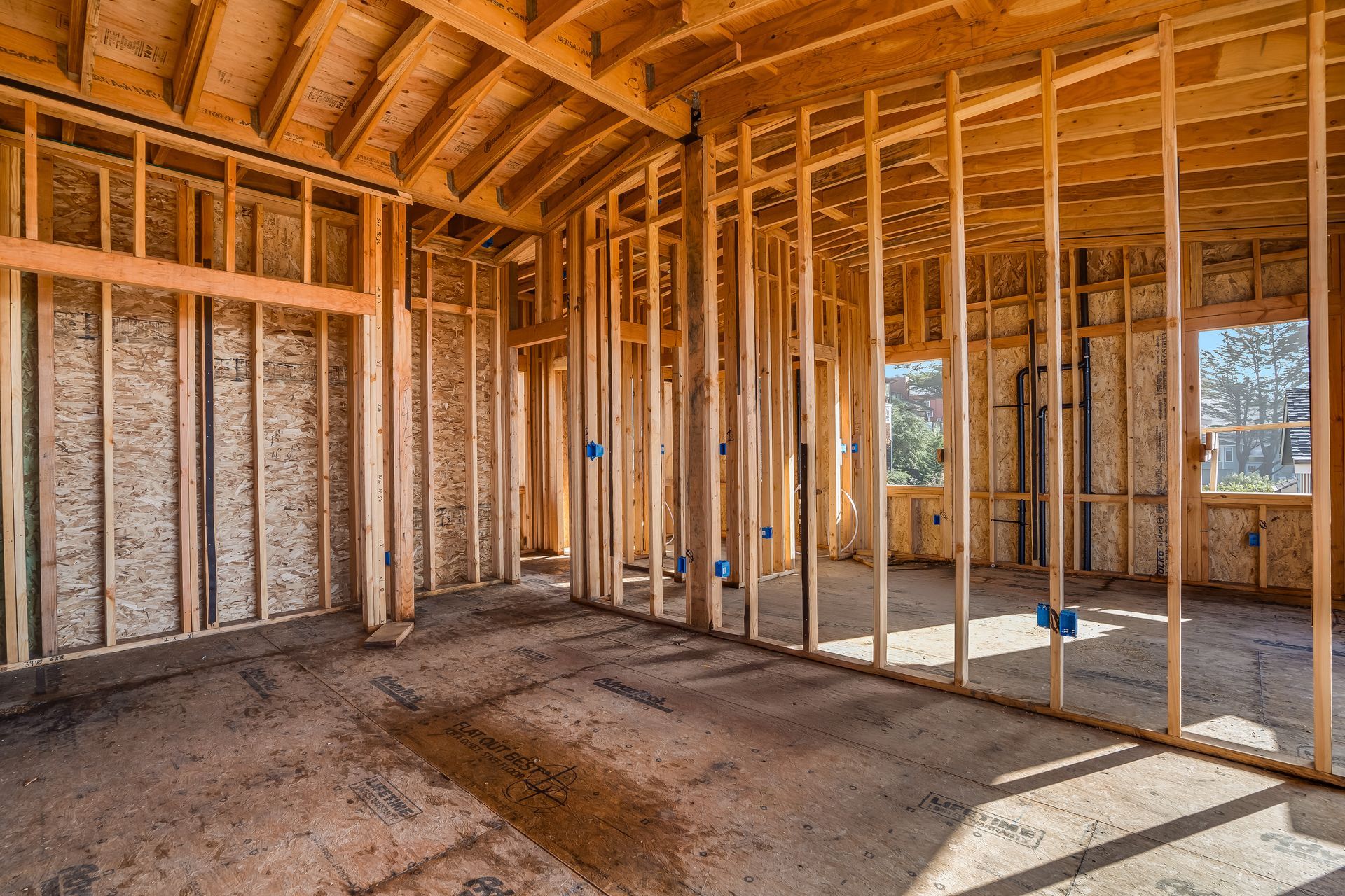 Interior of a building under construction, showing wooden frame, studs, and unfinished floors.
