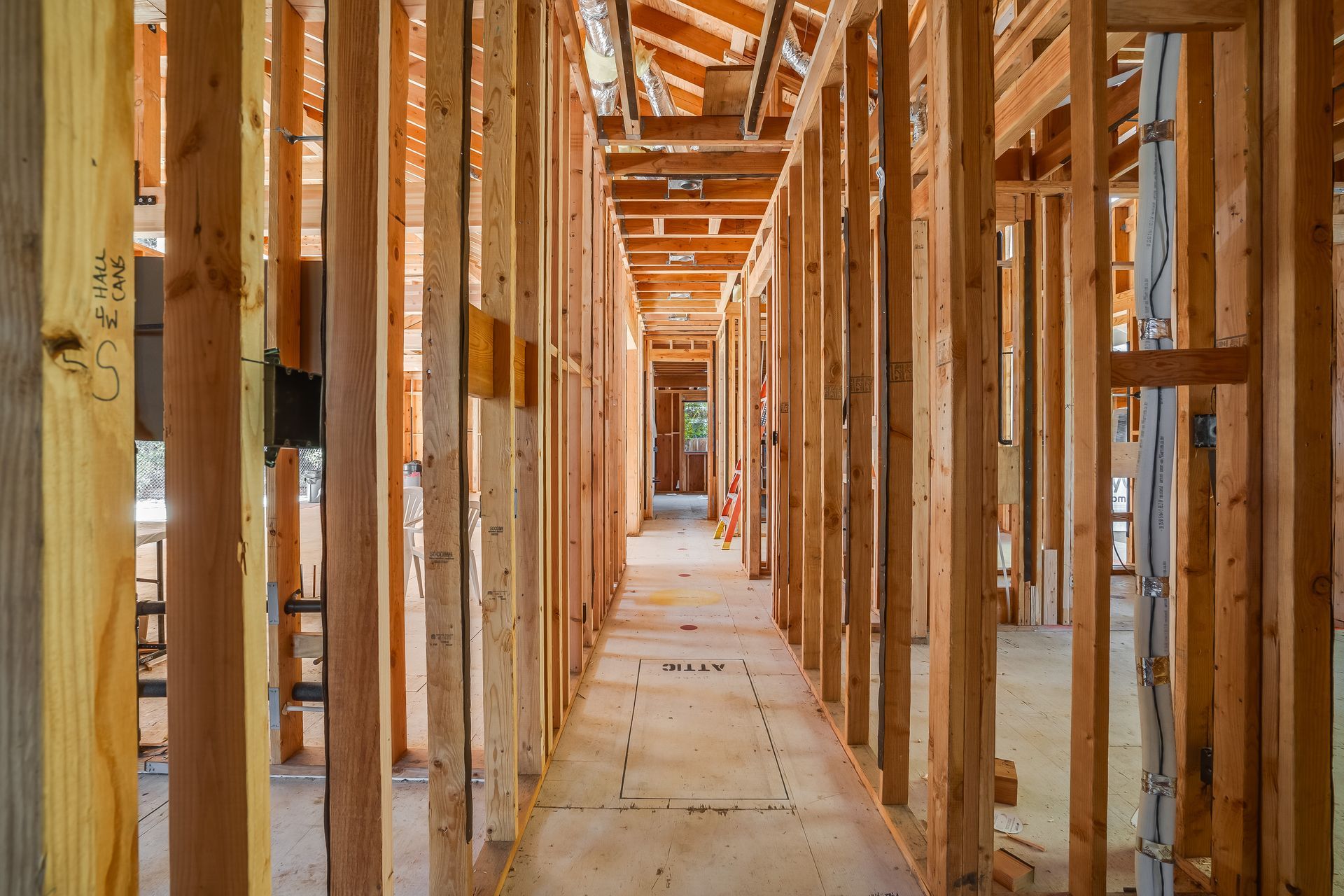 Interior view of a building under construction, showing wooden framing for walls and ceiling, forming a long hallway.