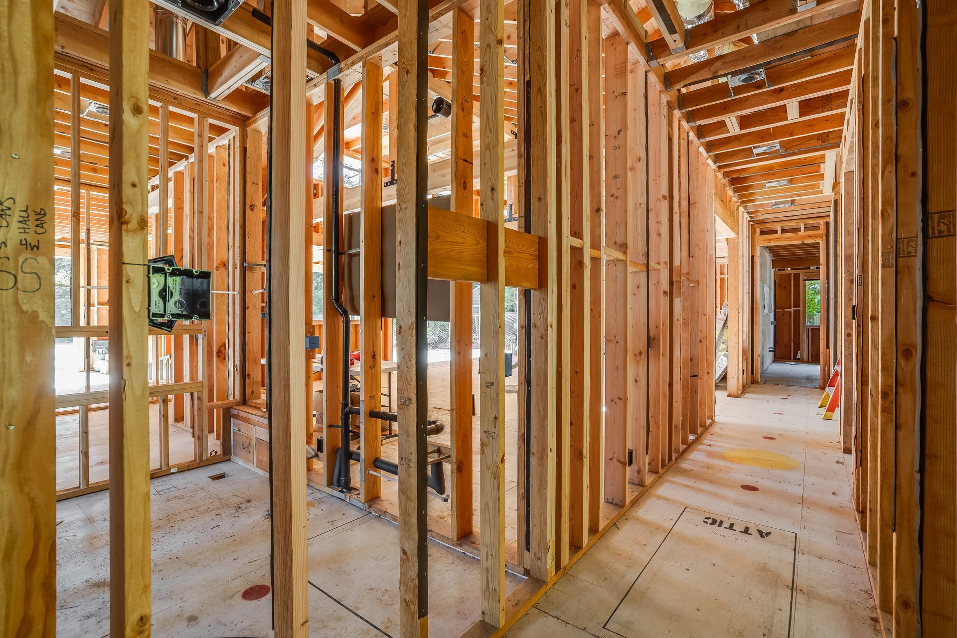Interior of a house under construction; wooden studs create walls and hallway.