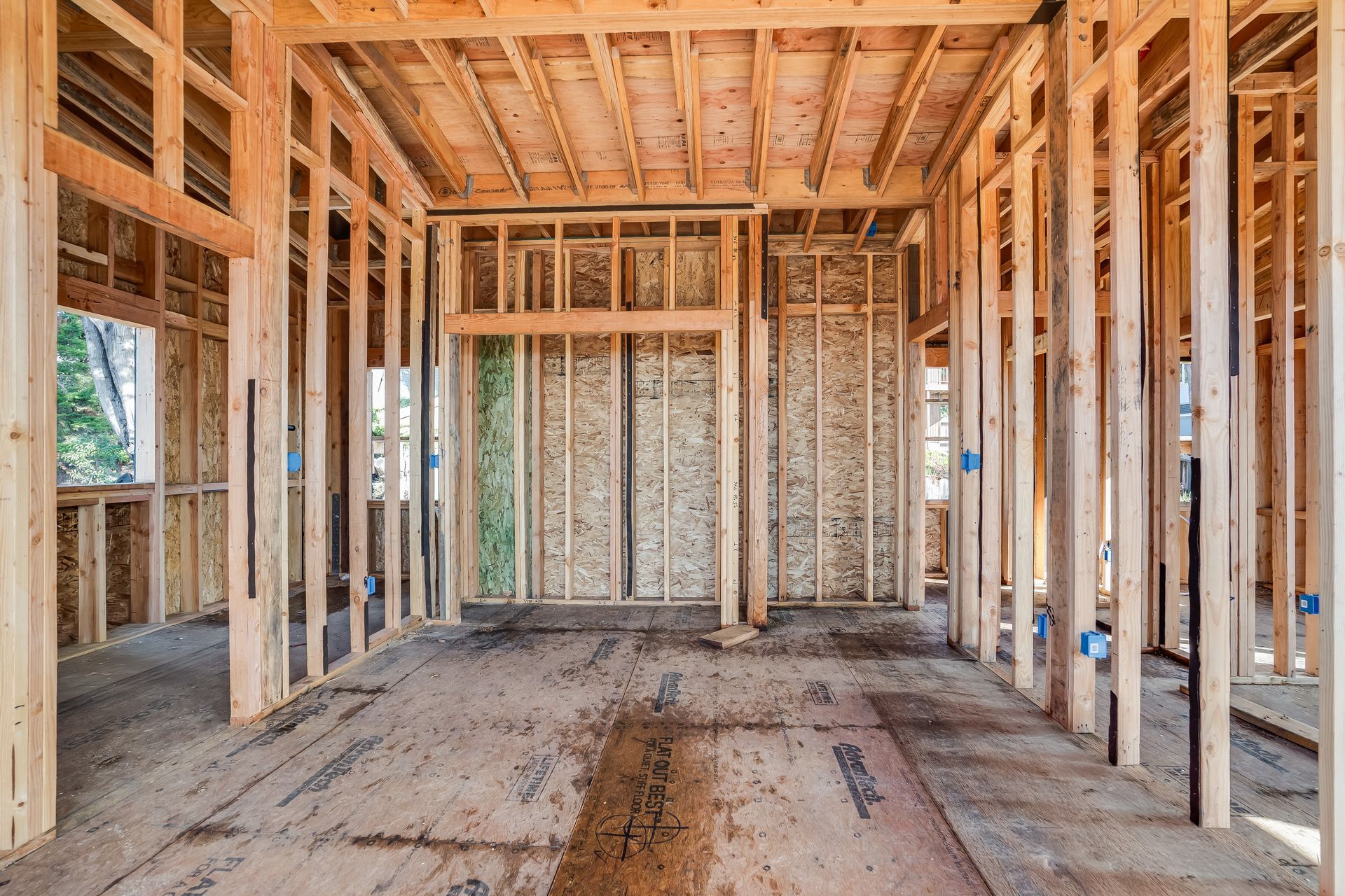 Interior view of a building under construction, showing wooden framing and unfinished floors.