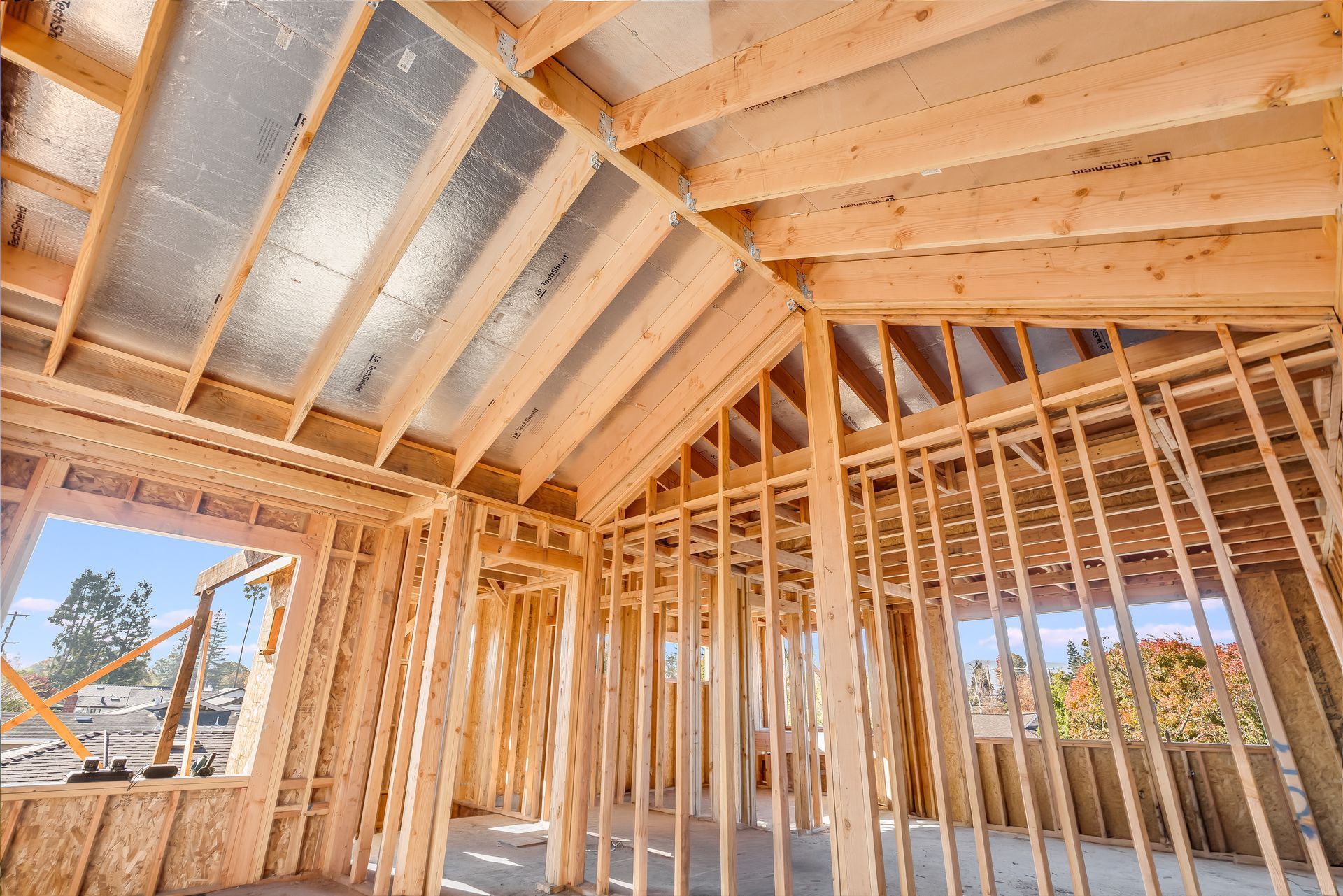 Interior of a house under construction; wooden framing, roof, windows.