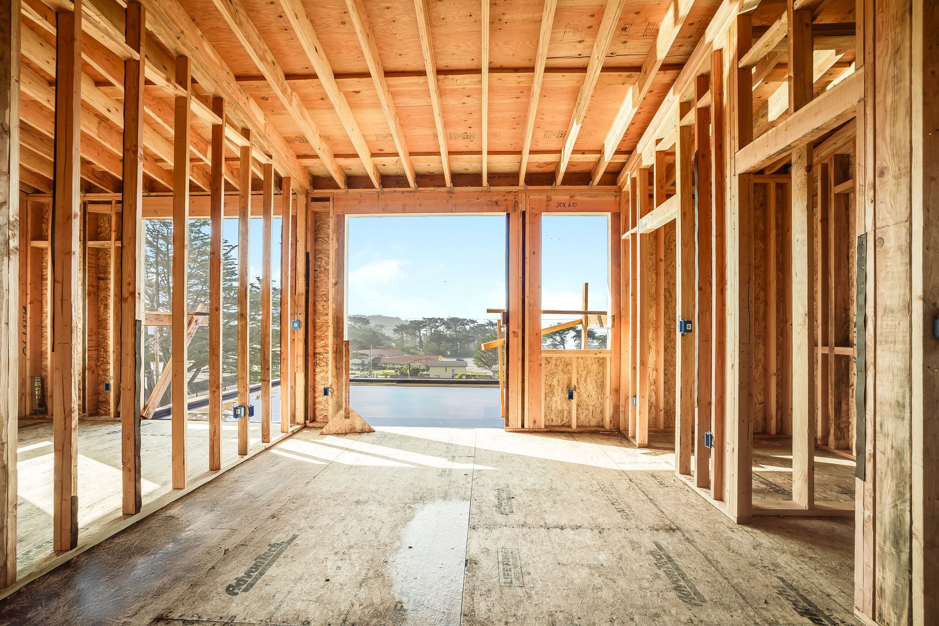 Interior view of a building under construction, framed with wooden studs and exposed beams.