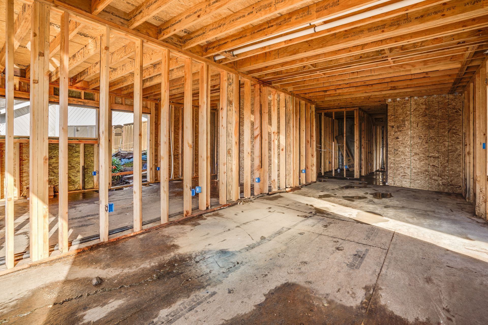 Wooden house frame under construction. Interior view with concrete floor and exposed beams.