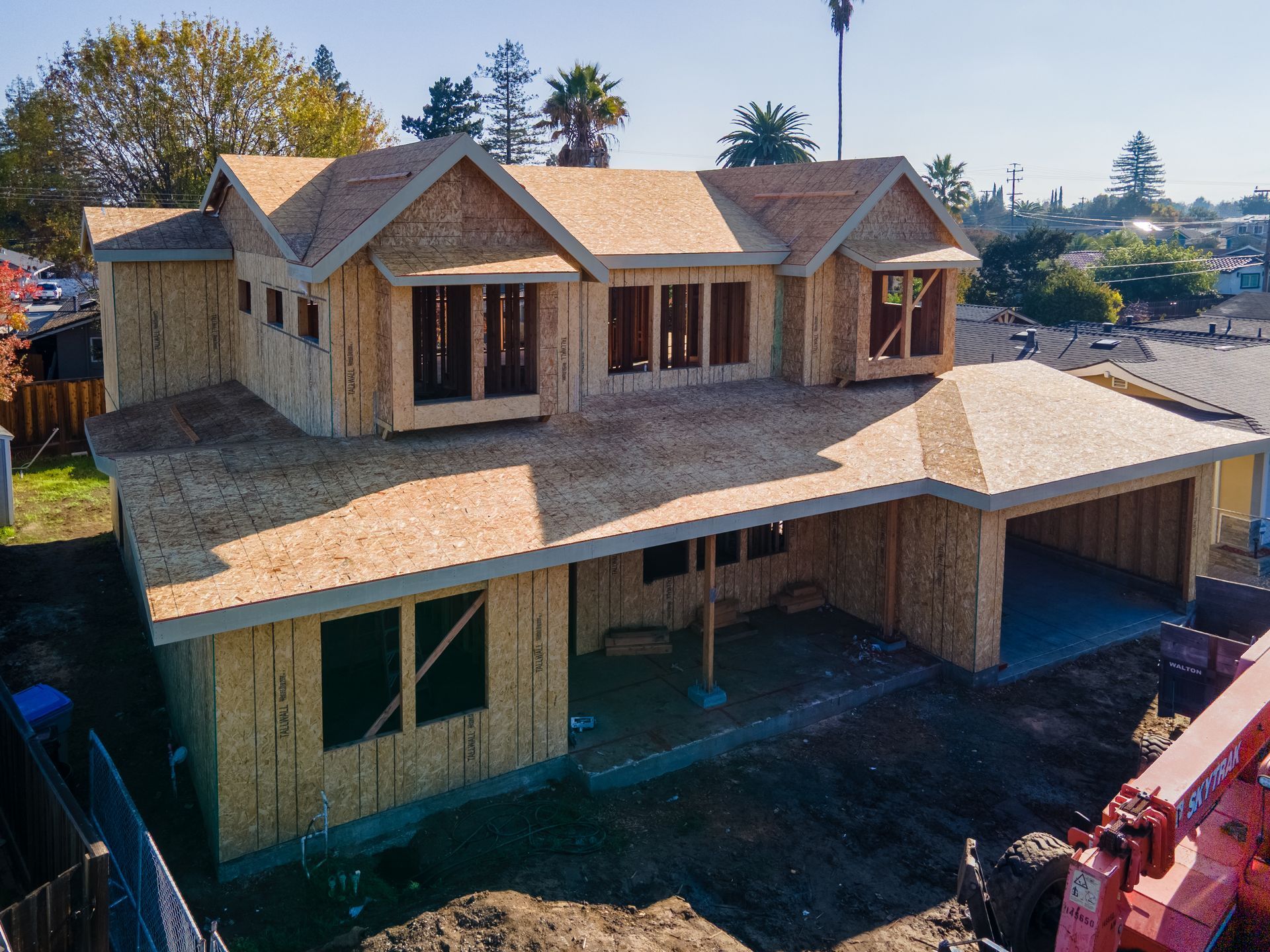 House under construction with exposed wooden framing and plywood roof.