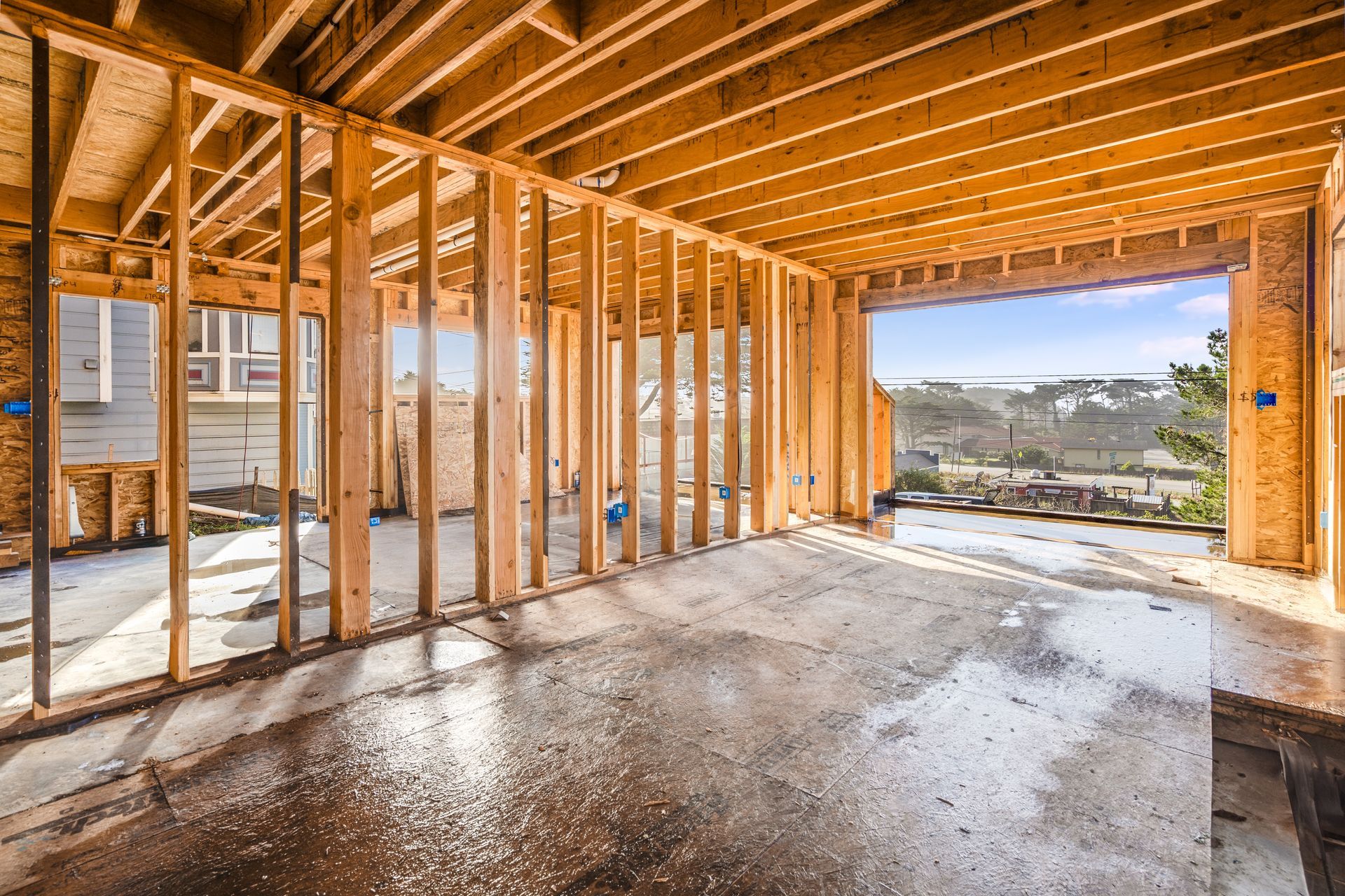 Interior view of a building under construction, framed with wooden studs, open to outdoor view.
