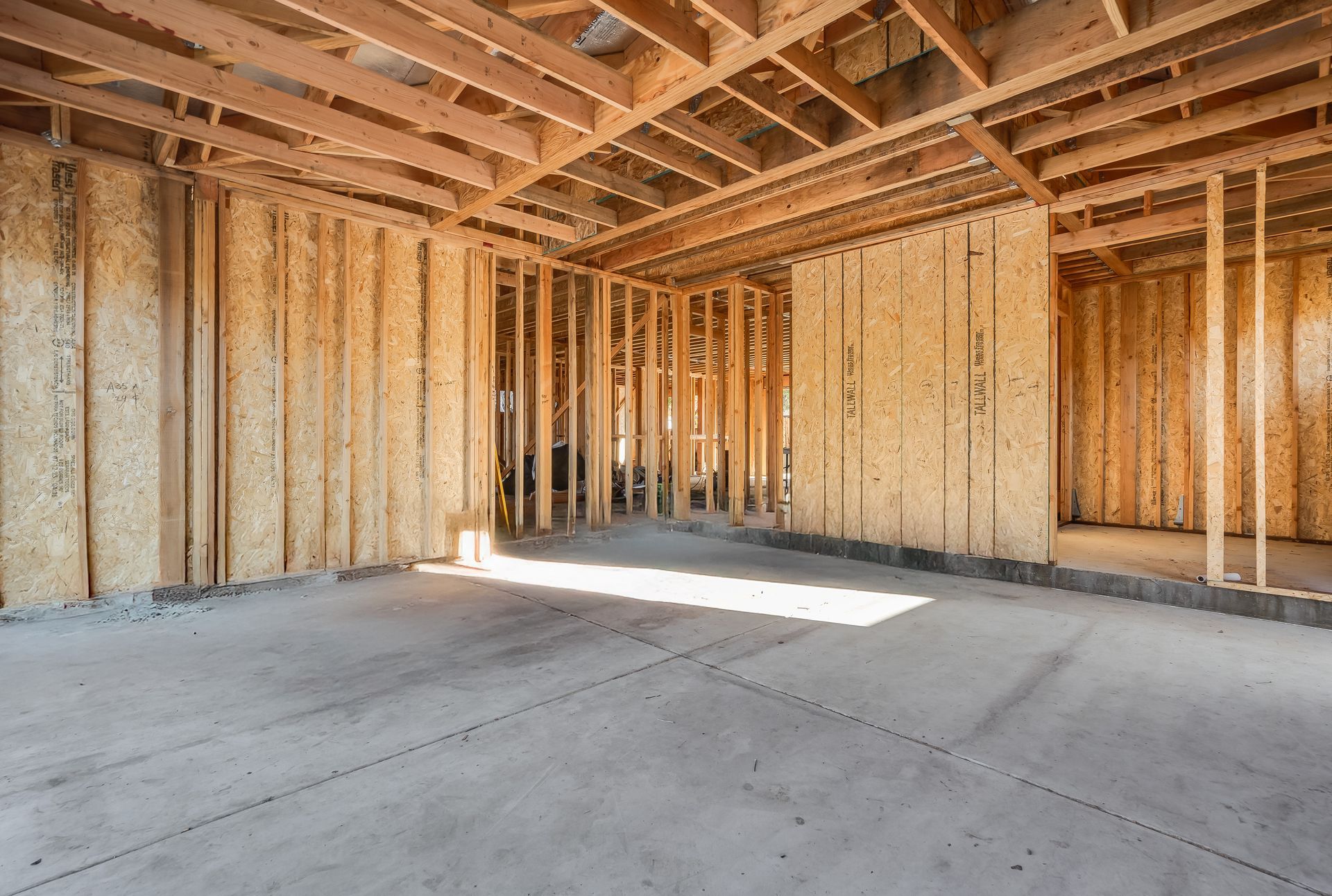 Interior of a building under construction, showing wooden framing and concrete floor.