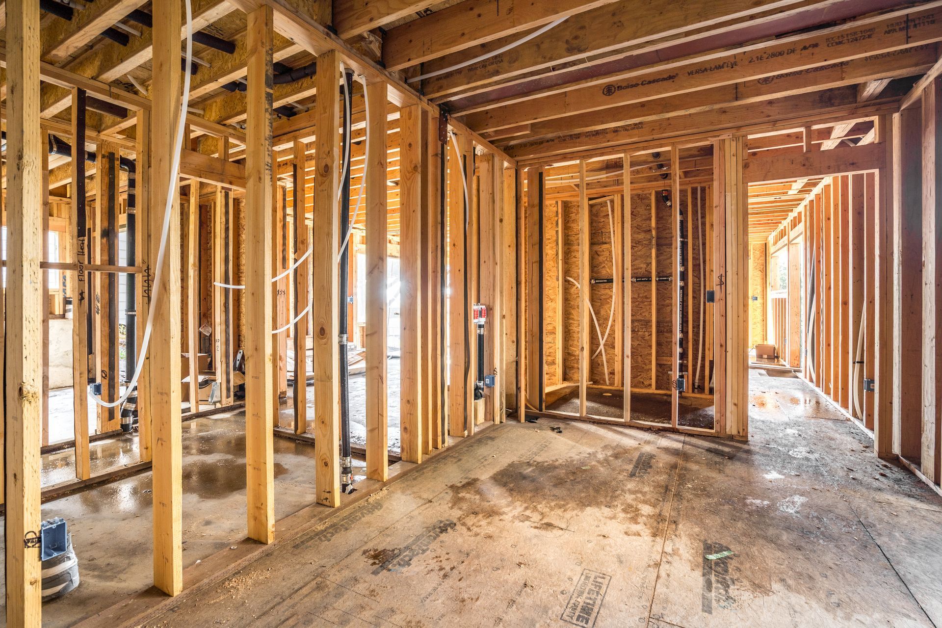 Interior of a building under construction, showing wooden framing and exposed pipes.