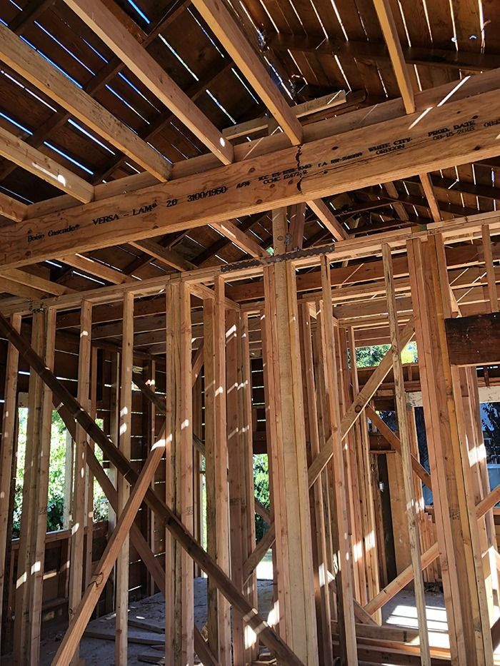 Wooden frame of a building under construction, showing beams, studs, and rafters.