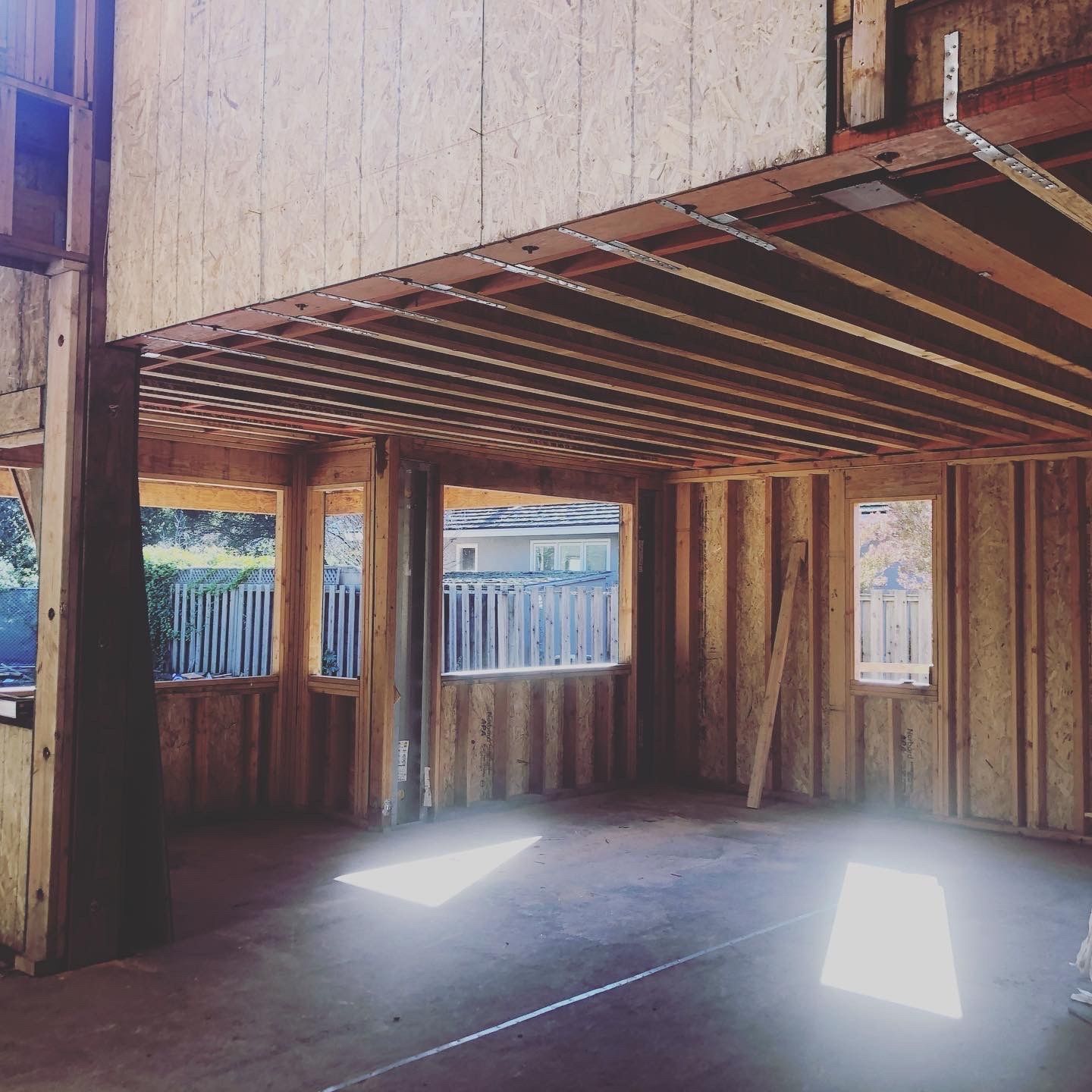 Interior of a building under construction, wooden frames with windows and a second-story floor.