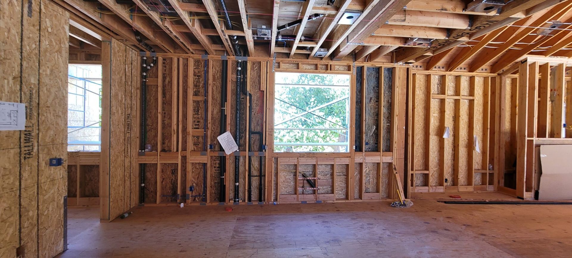 Interior of a building under construction, showing wooden framing and exposed ceiling beams.