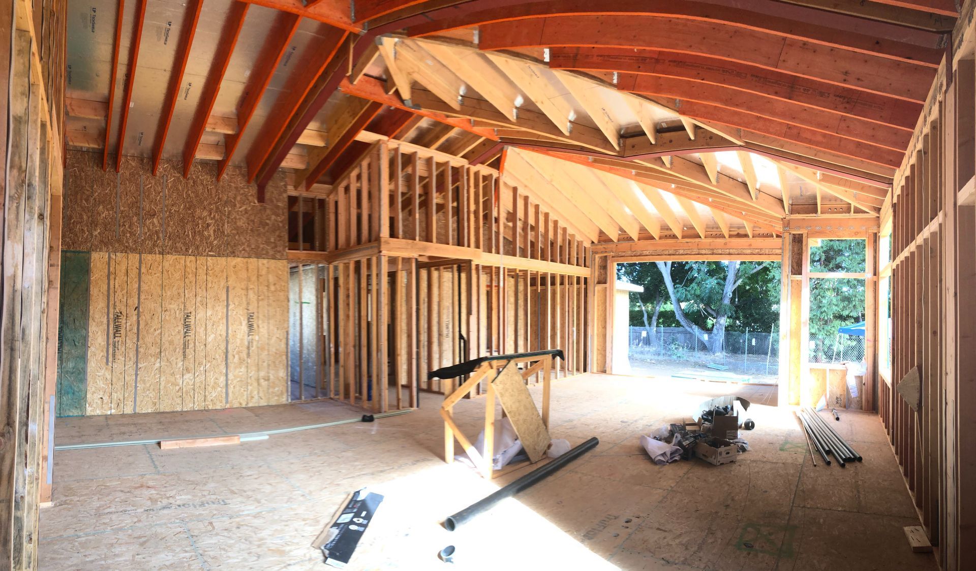 Interior view of a building under construction, showing wooden framing and exposed beams with a large window.