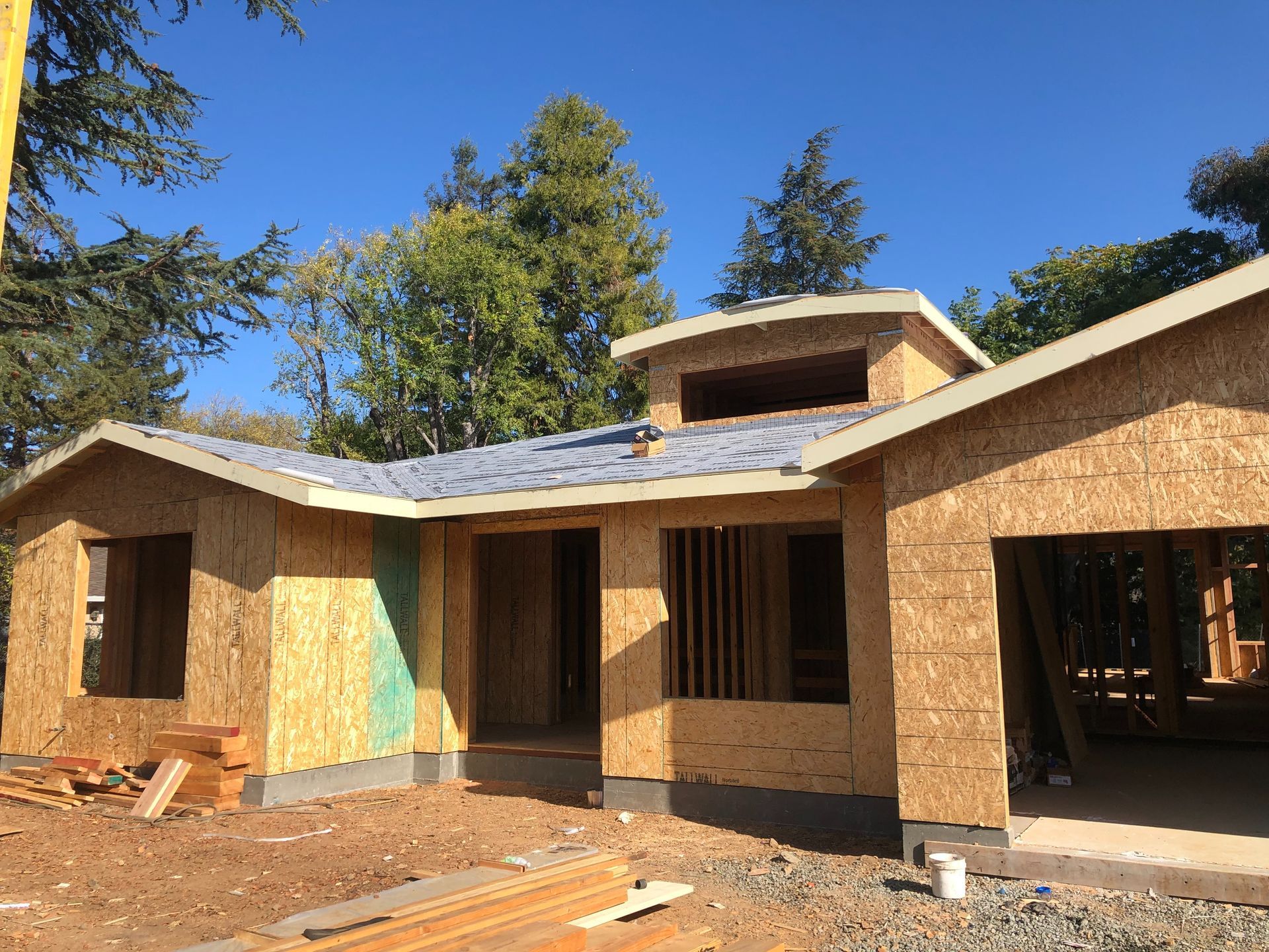 A house under construction. Exterior walls are plywood. Unfinished roof and windows.