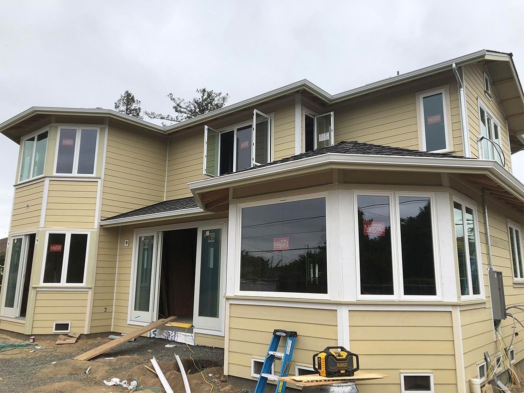 House under construction with beige siding, white trim, and multiple windows.