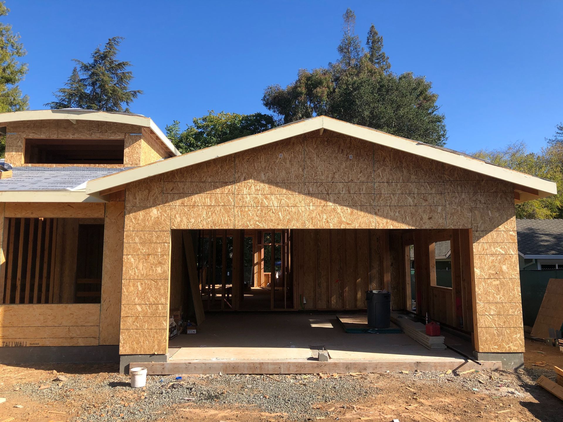 Garage under construction with open door frame, OSB walls, and blue sky background.