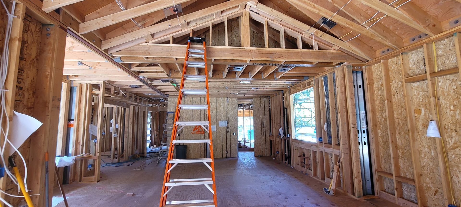 Interior of a house under construction. Wooden framework, a ladder, and a window are visible.