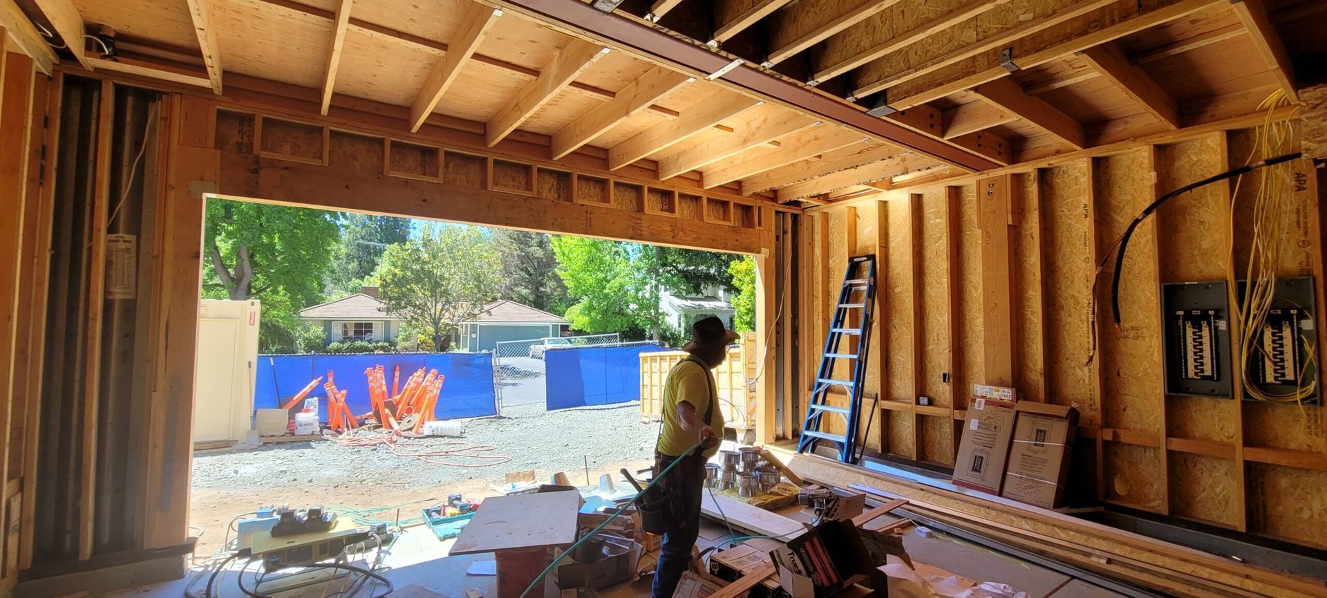 Construction worker inside unfinished garage doorway, looking out. 