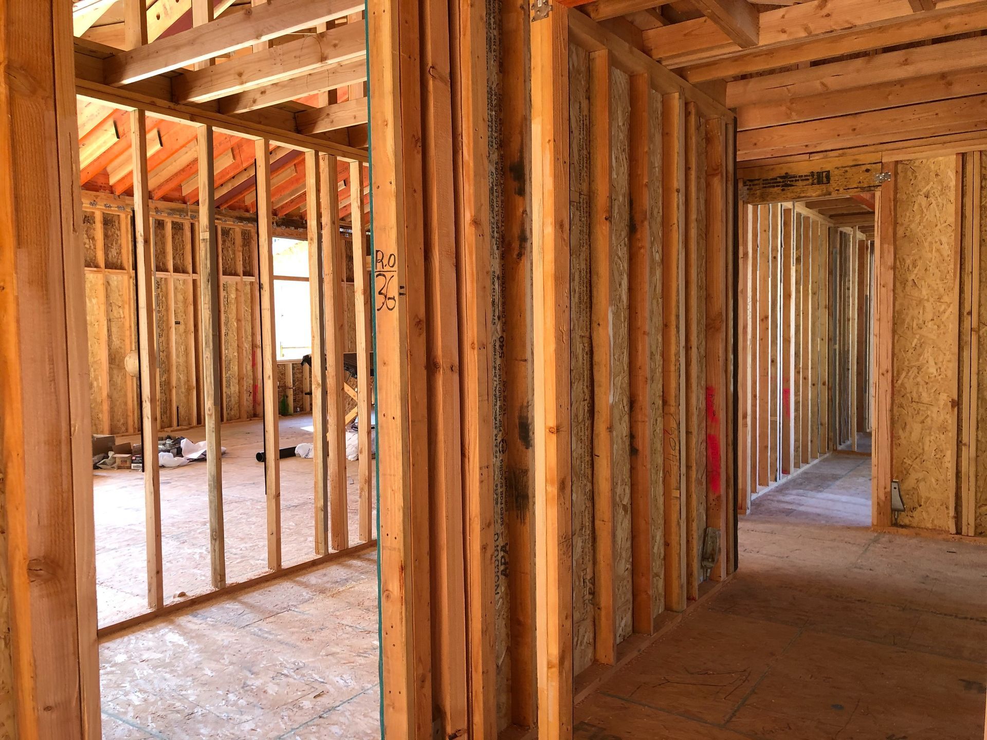 Interior view of a building under construction, showing wooden framing for walls, doorways, and a hallway.